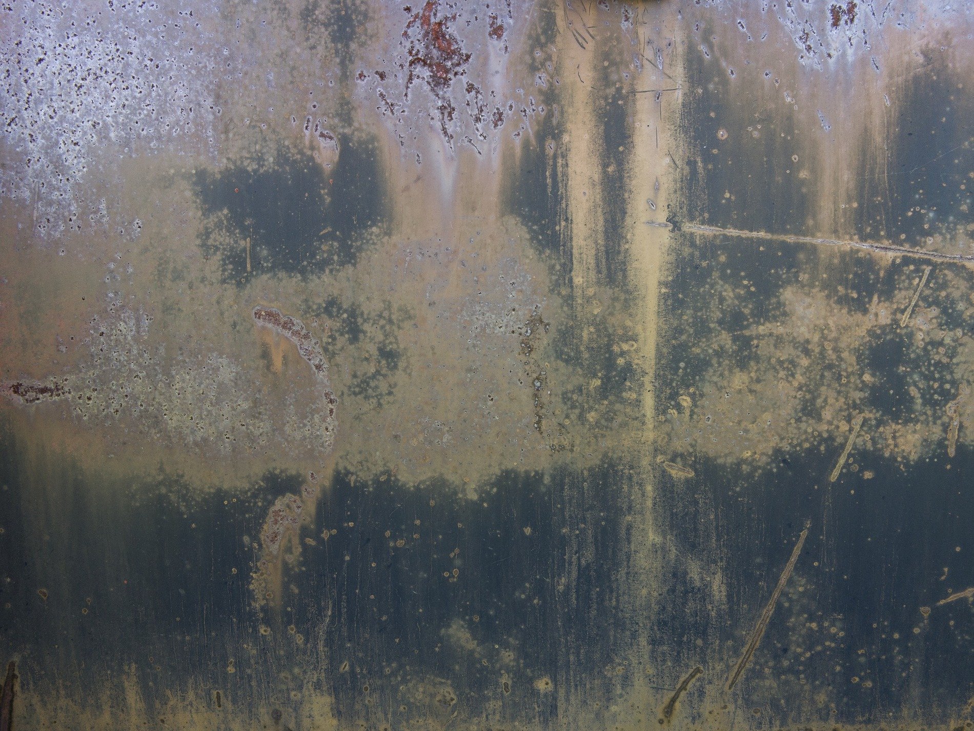 Rust blooms on the steel, vertical streaks stain the dark, weathered metal skin