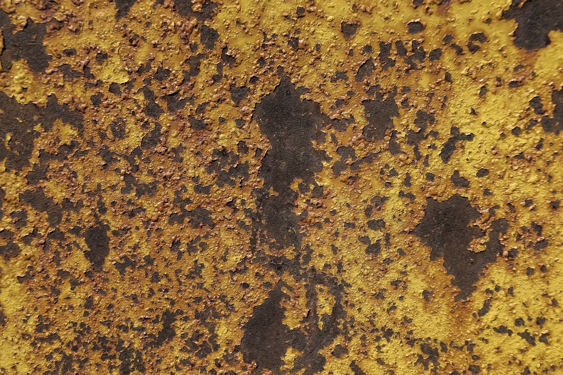 Yellow paint flakes off, dark iron blooms with orange grit, metal turns to dust