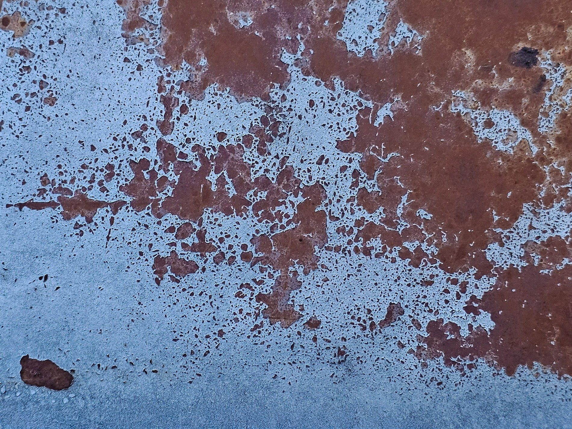 Blue paint flakes away, orange rust blooms on the steel, rust claims the finish