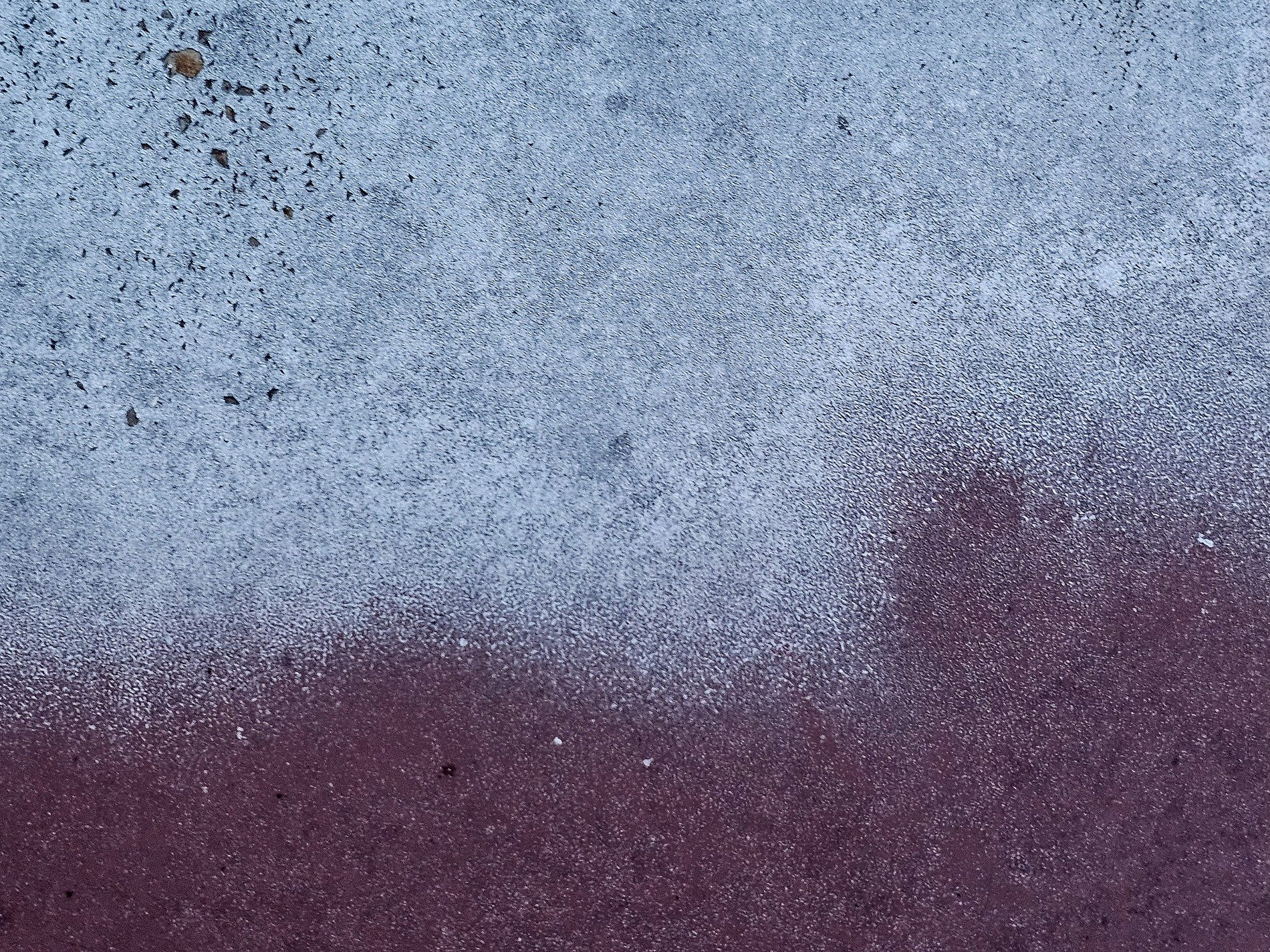 Pale blue dust descends, maroon surface waits below, speckles mark the line