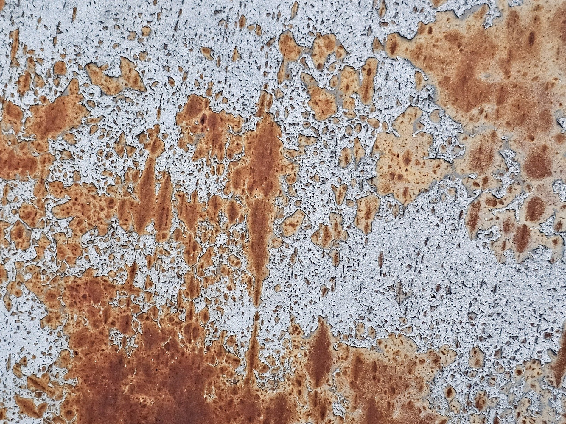 White paint flakes away, orange rust maps the surface, iron meets the air