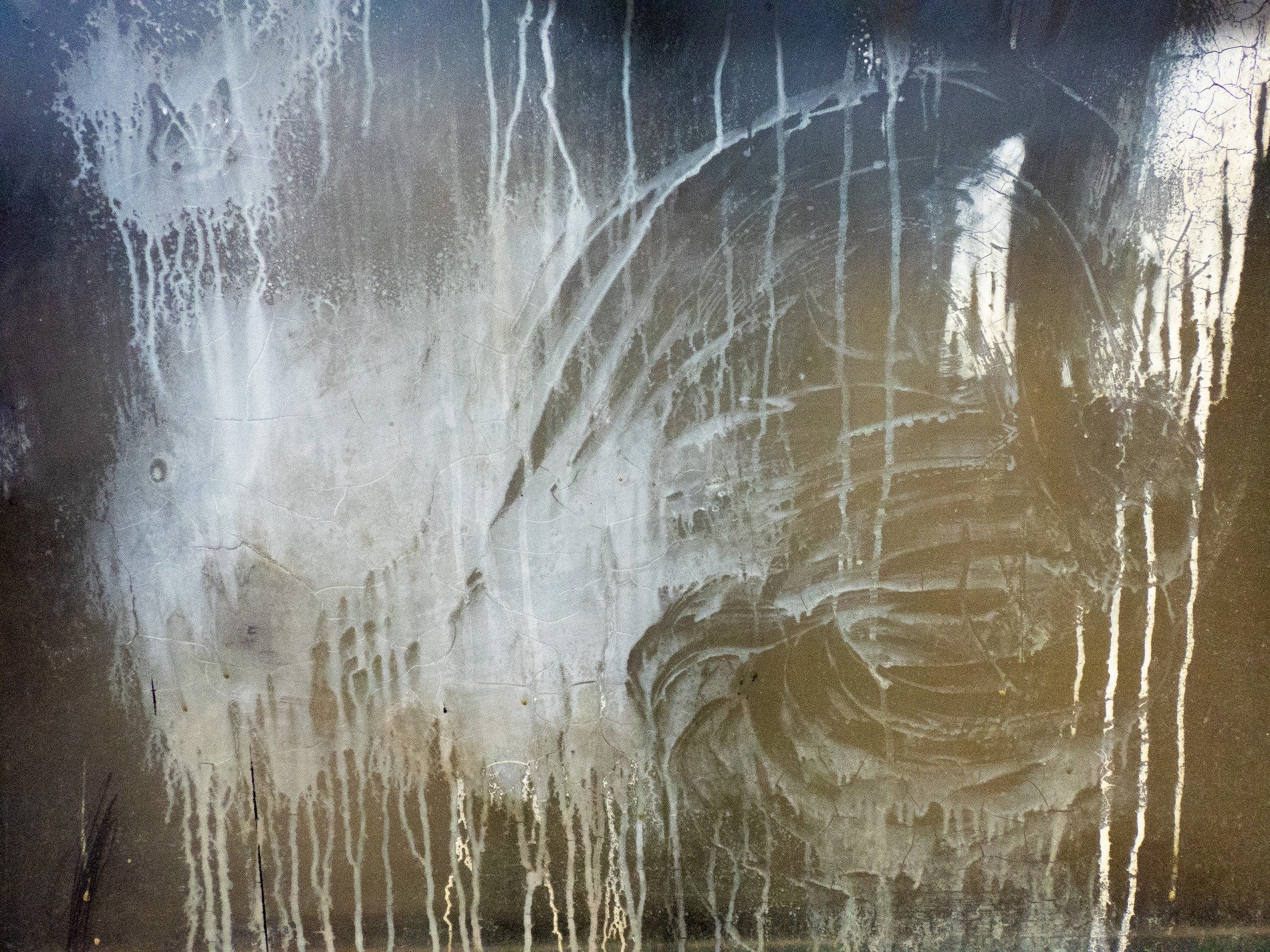 Pale drips stain the dark, swirls of white across the grime, ghosts of motion stay