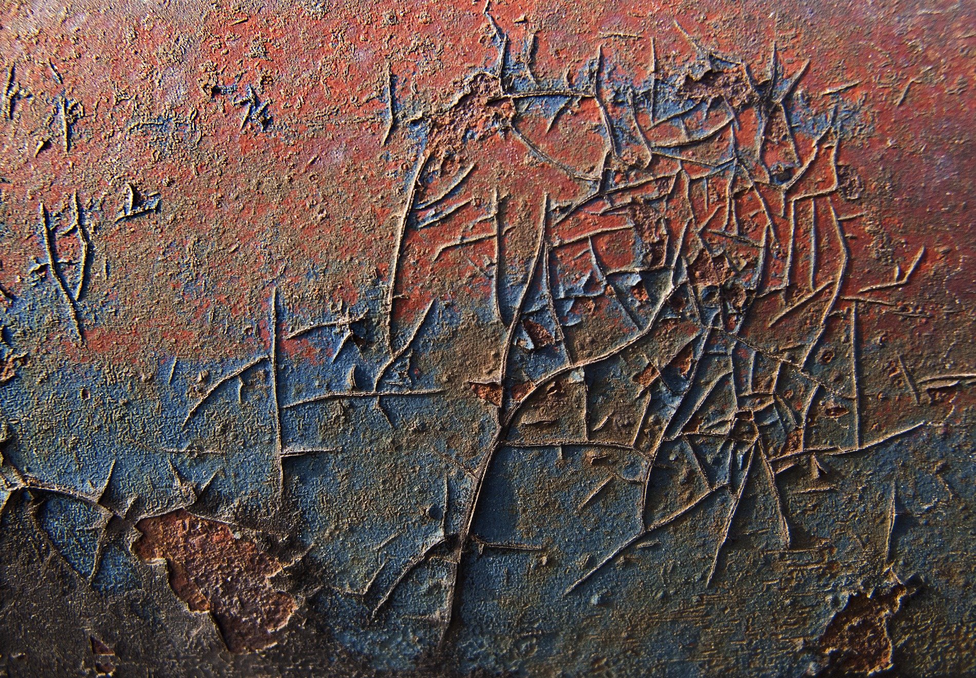 Blue paint meets the rust, orange veins bleed on the steel, grit holds the pattern