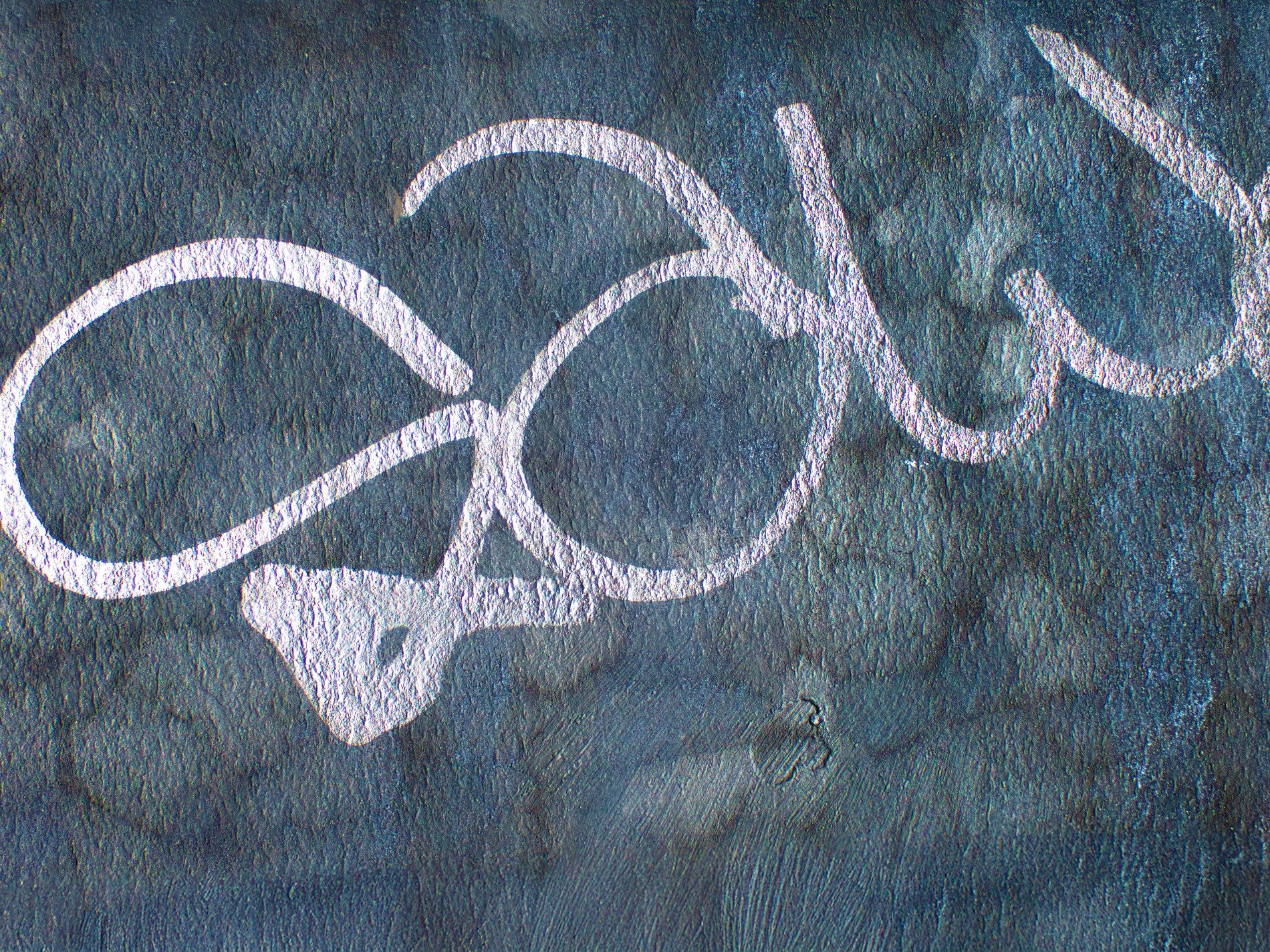 Blue paint on the window, jagged flakes meet the clear glass, light catches the grit