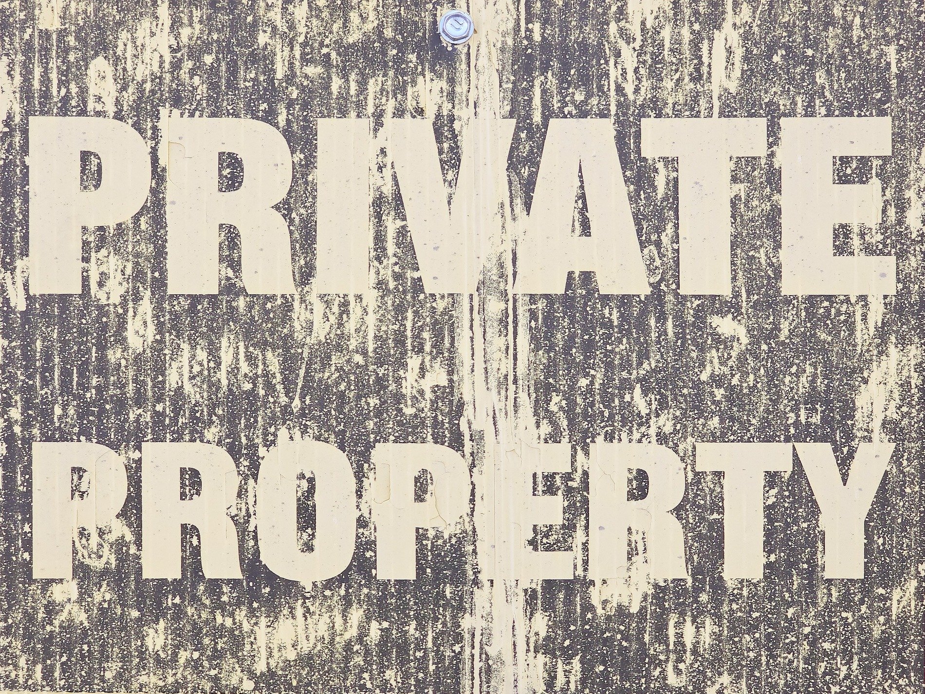 Bold words on the sign, yellow streaks the faded brown, weather claims the board