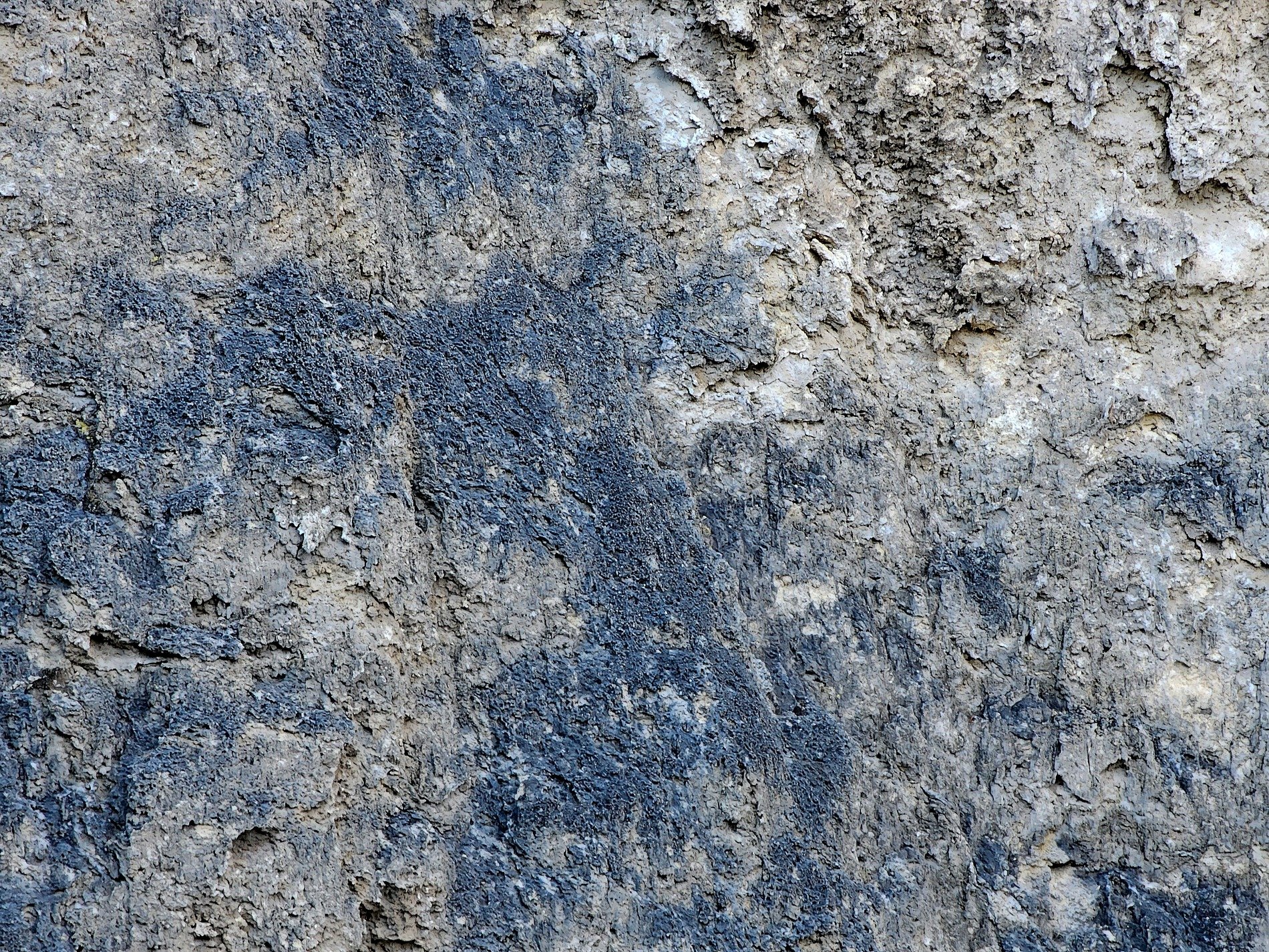 Grey stone wears its age, blue stains bleed through weathered crust, layers fall to dust