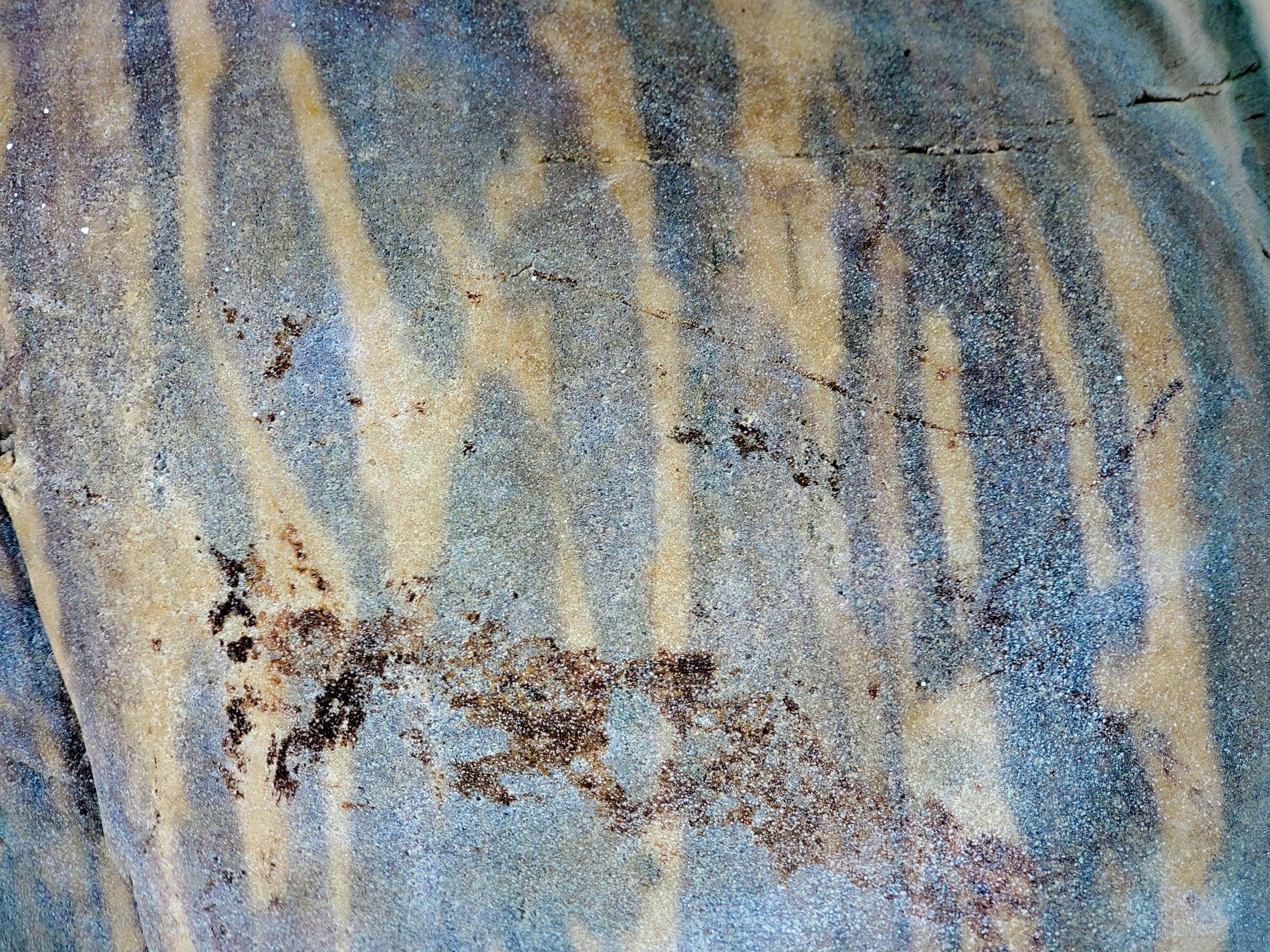 Grey waves meet the sand, stripes of time across the rock, silent patterns wait