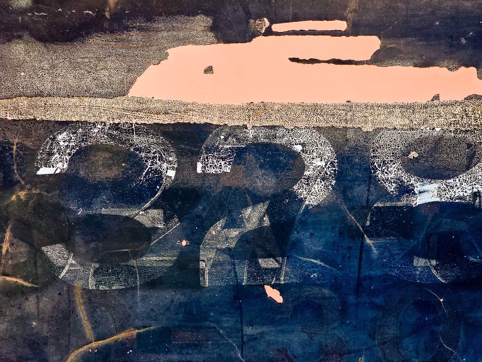 Cracked white ink remains, salmon patches on dark blue, metal tells a tale.