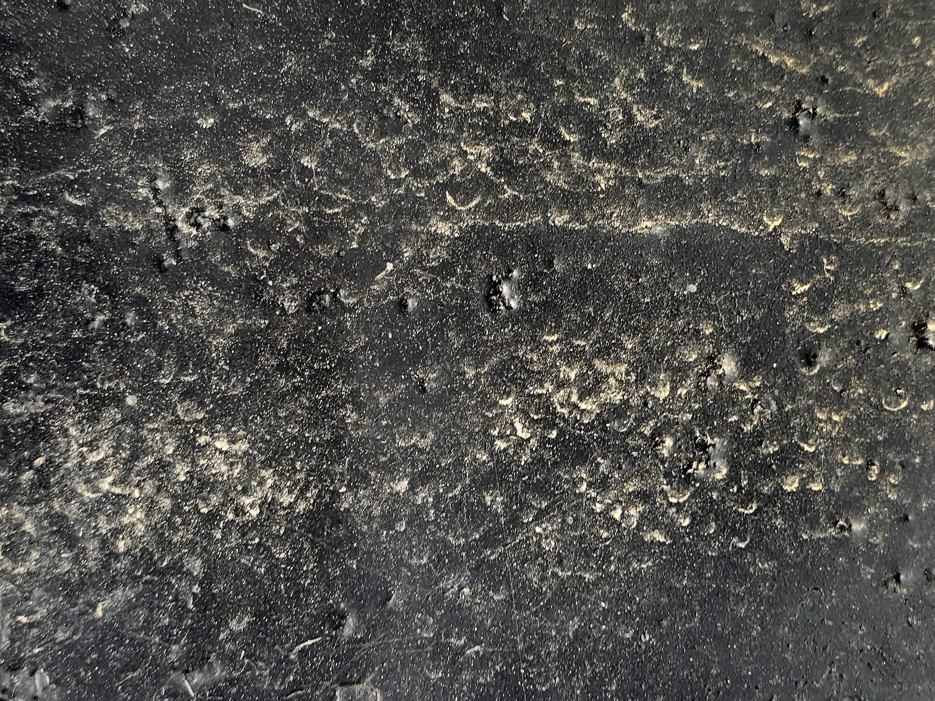 Dark paint pits and bumps, black skin holds the sandy grit, night meets heavy dust