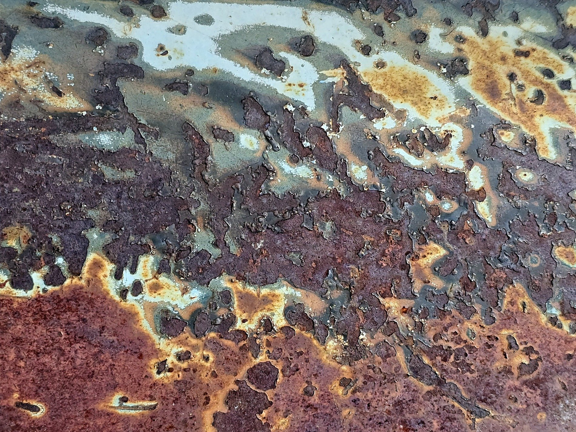 Deep rust eats the blue, jagged edges on the steel, decay takes the light