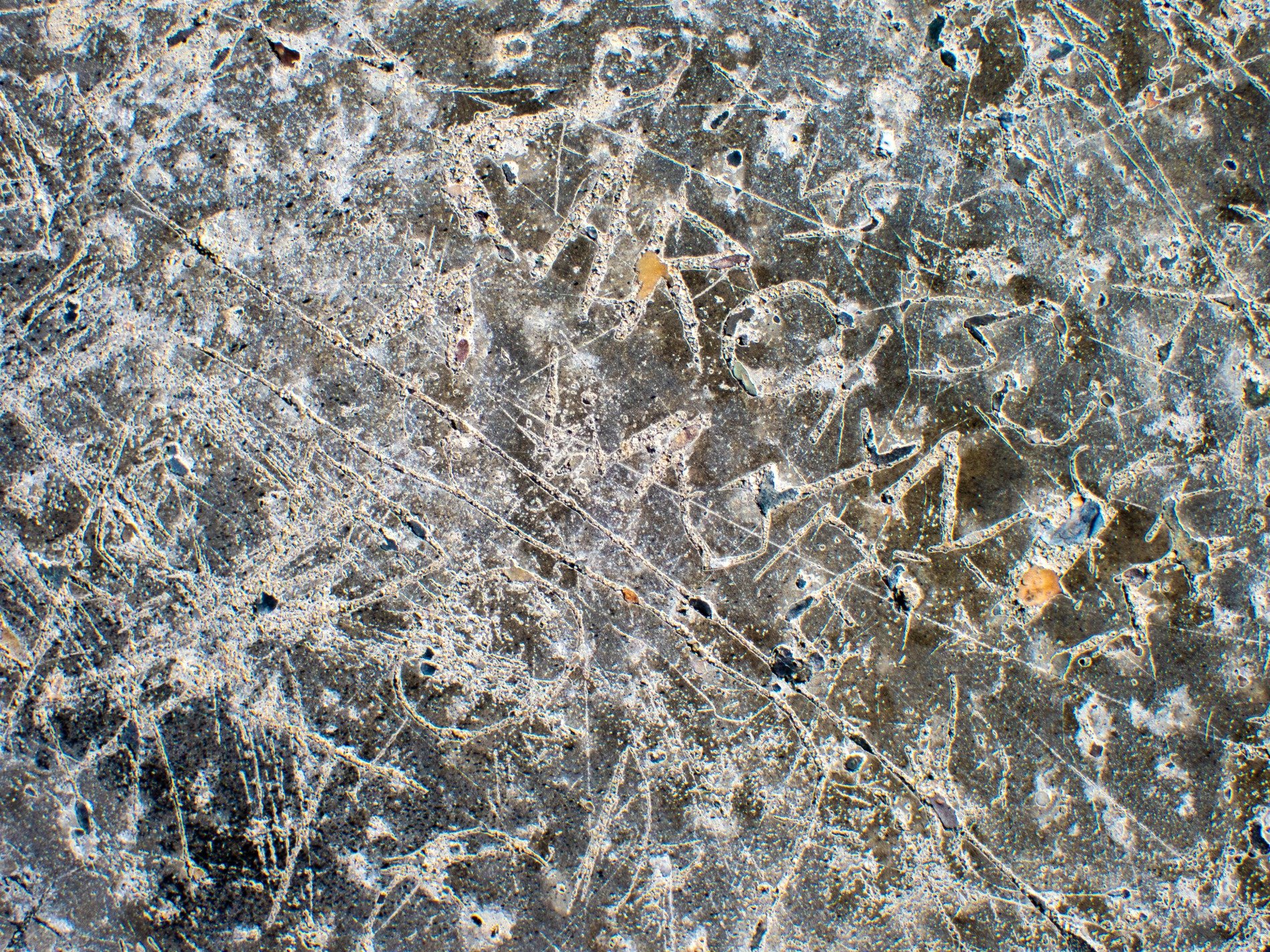 Etched lines in stone, jagged marks trace the table, time carves the grit