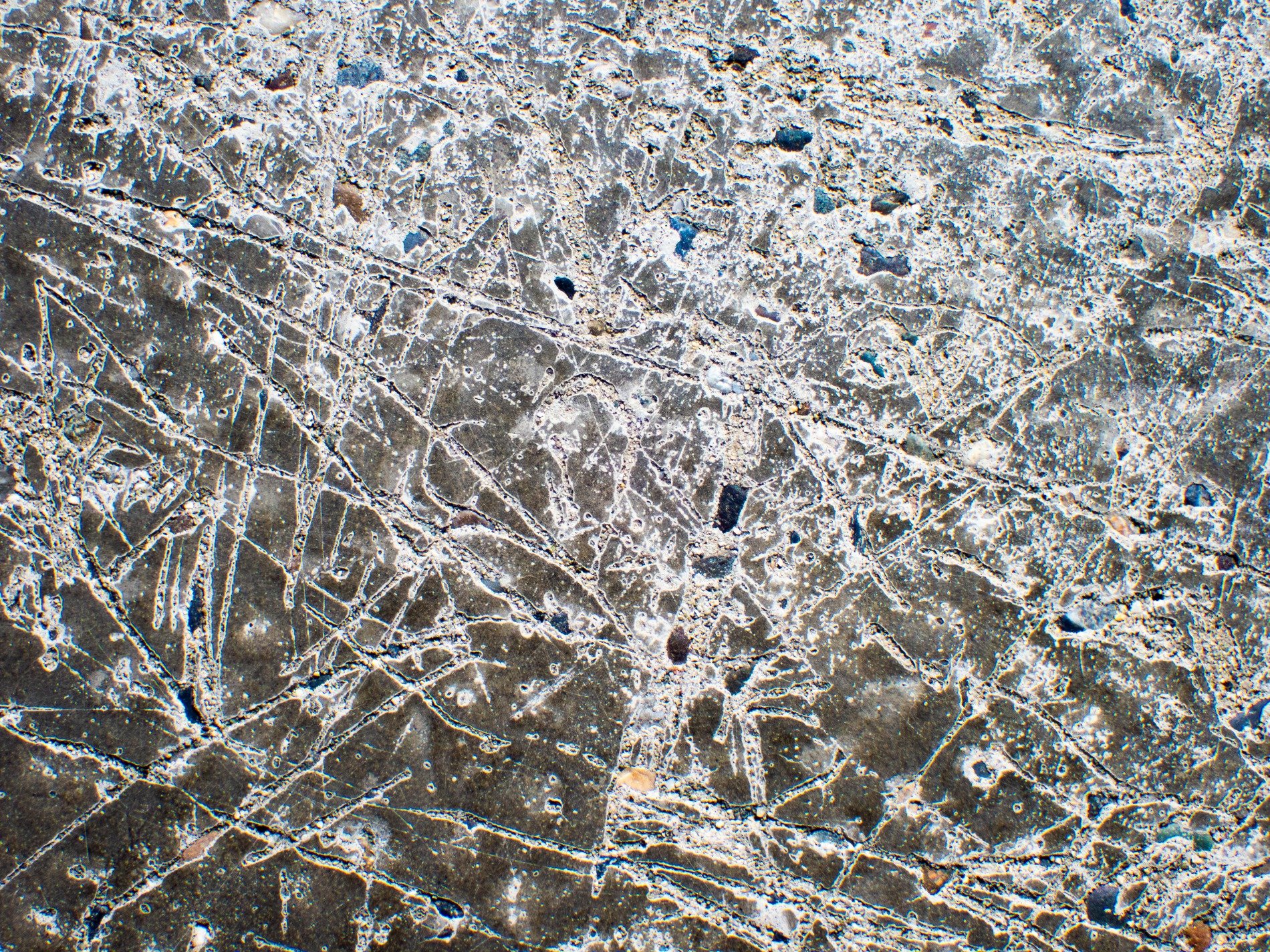 Scars on ancient stone, white dust fills the jagged lines, earth carved deep by time