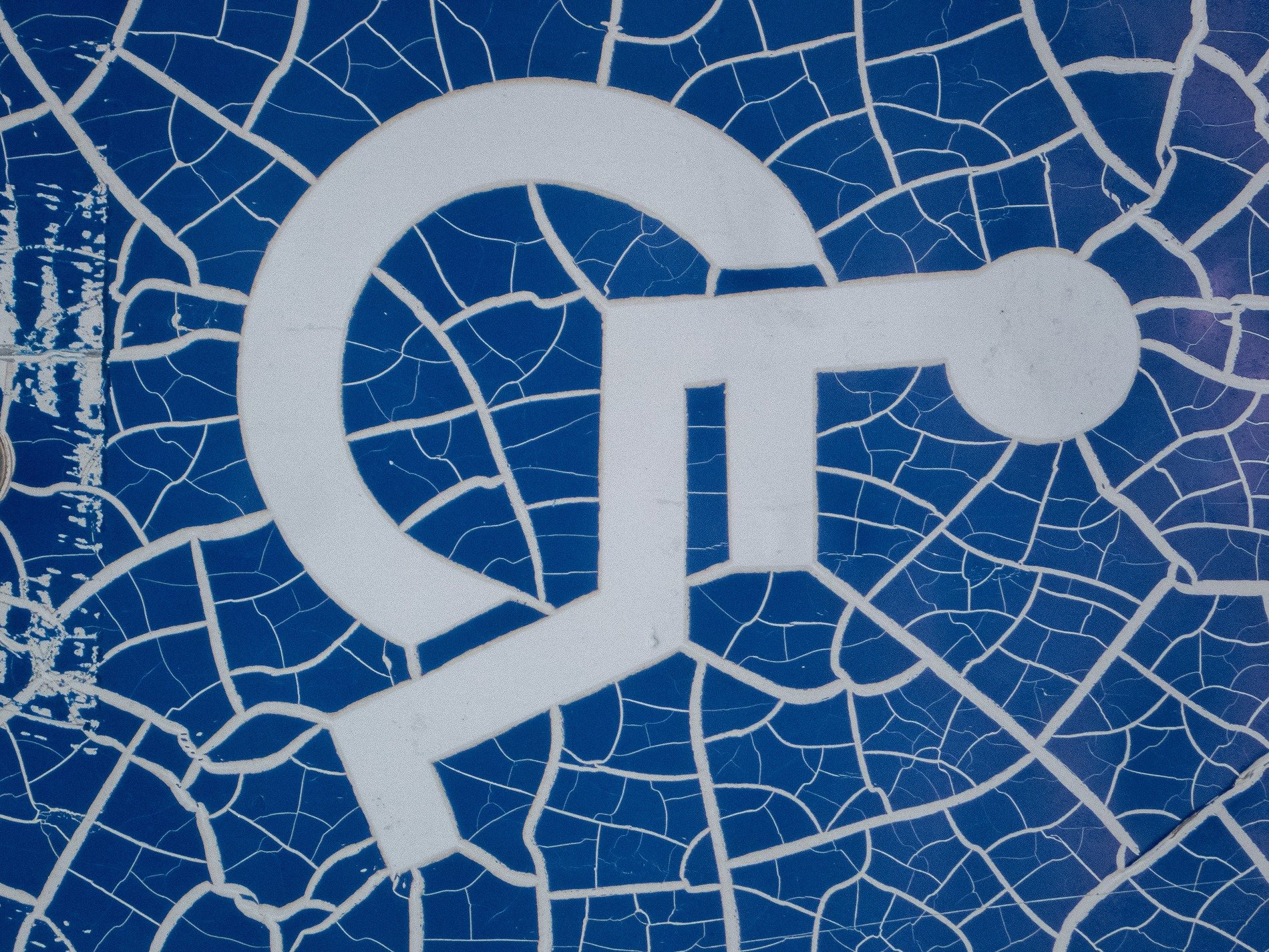 Blue paint webs apart, white lines break in tiny shards, time cracks the symbol