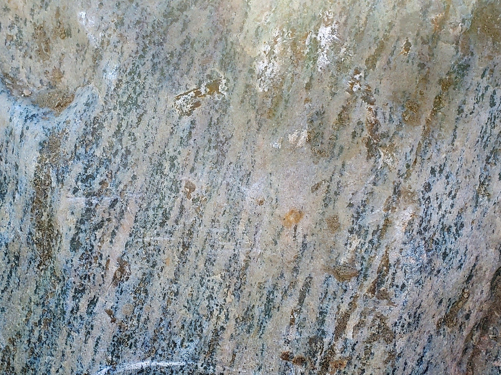 Grey grains flow in lines, vertical veins trace the skin, mineral stays deep