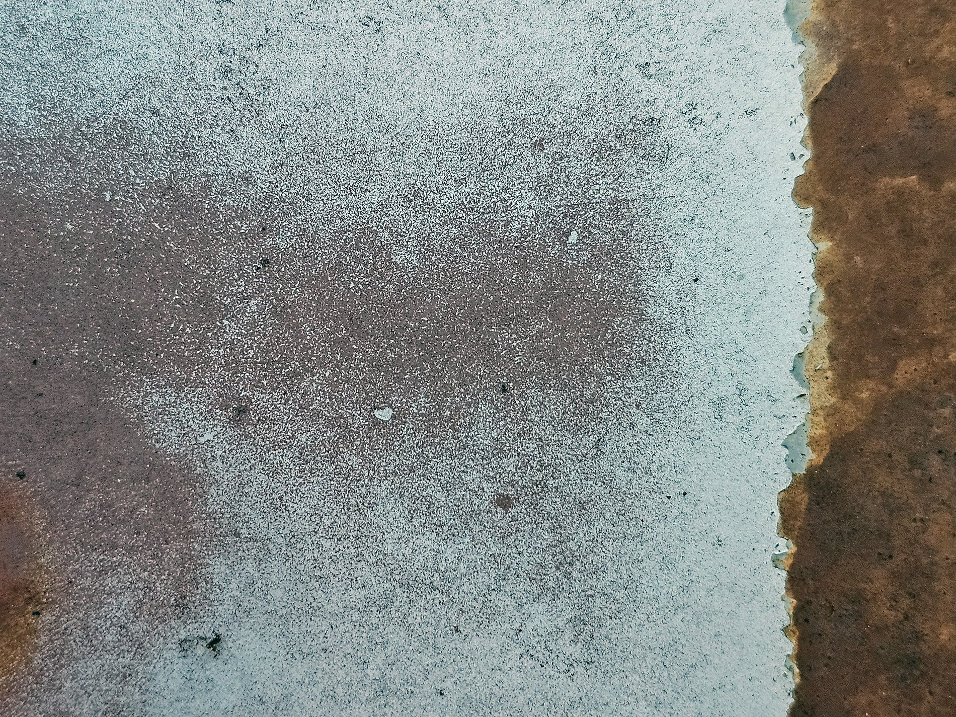 Grey paint meets the rust, a jagged shore on the steel, time claims the finish.