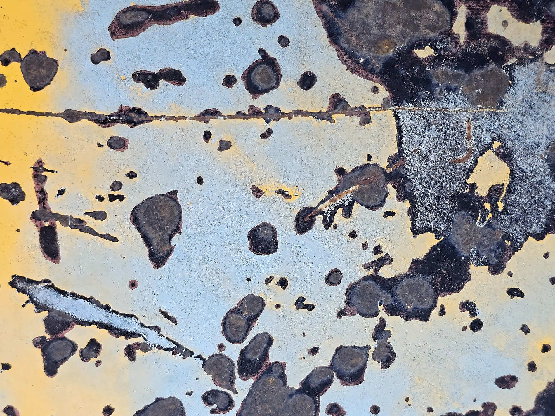 Blue paint starts to peel, dark rust blooms across the steel, yellow fades from sight