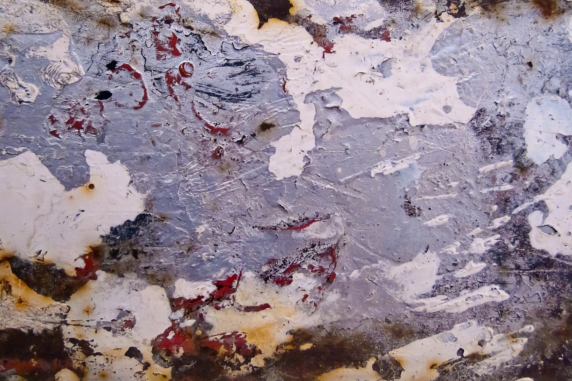 Grey paint peels away, white and rust layers emerge, grit marks the finish