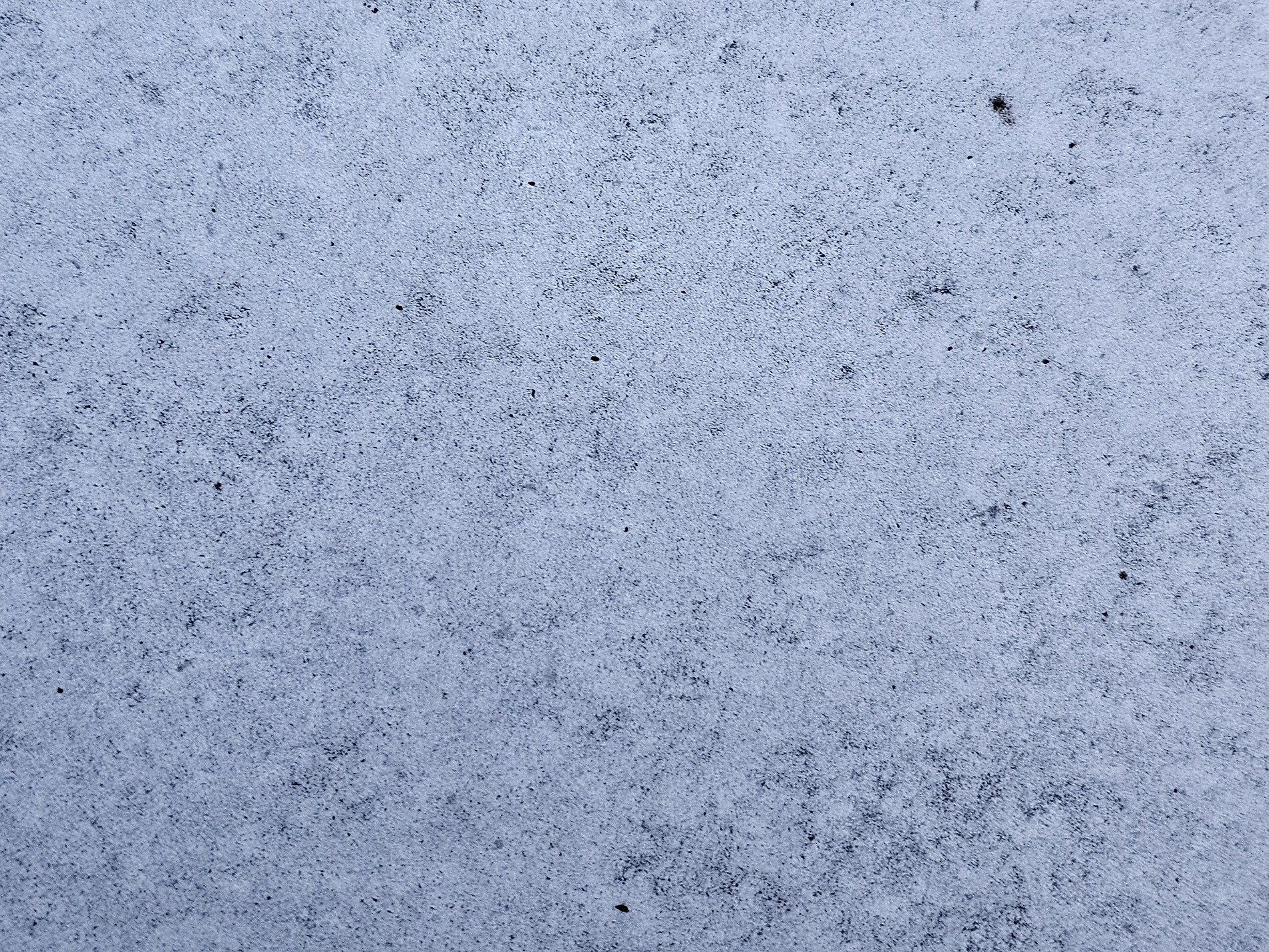 Pale blue surface waits, dark grains dust the frozen ground, silence in the stone