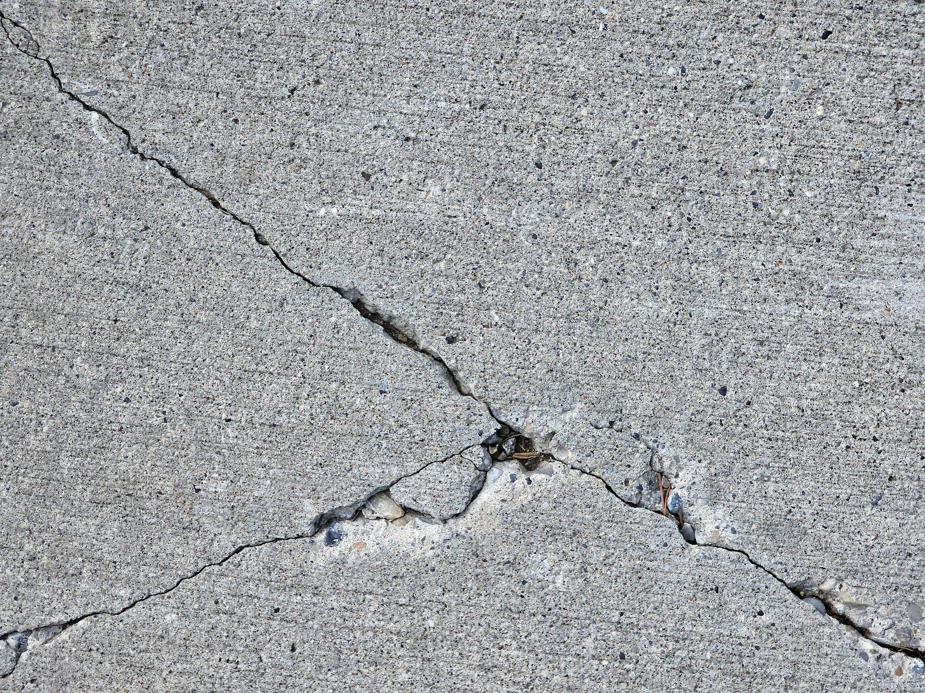 Grey stone splits apart, diagonal crack cuts deep, grit falls in the void