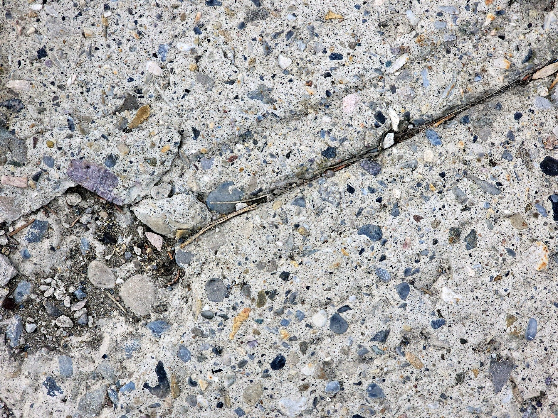 Grey stones in the mix, jagged crack splits the surface, grit meets the dry earth