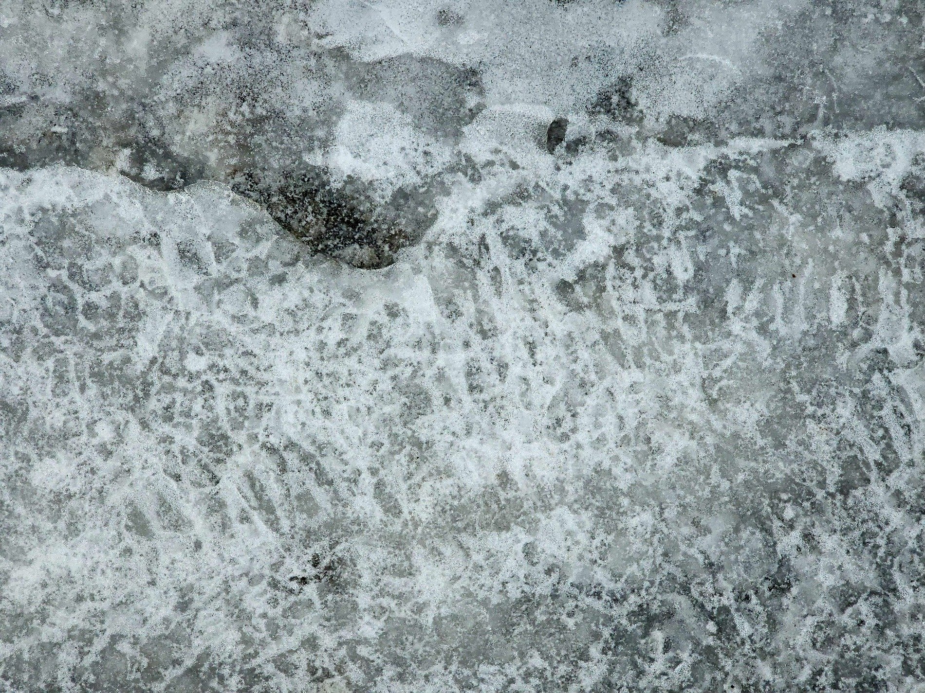 Frozen bubbles rise, grey stone sleeps beneath the ice, winter's hard embrace