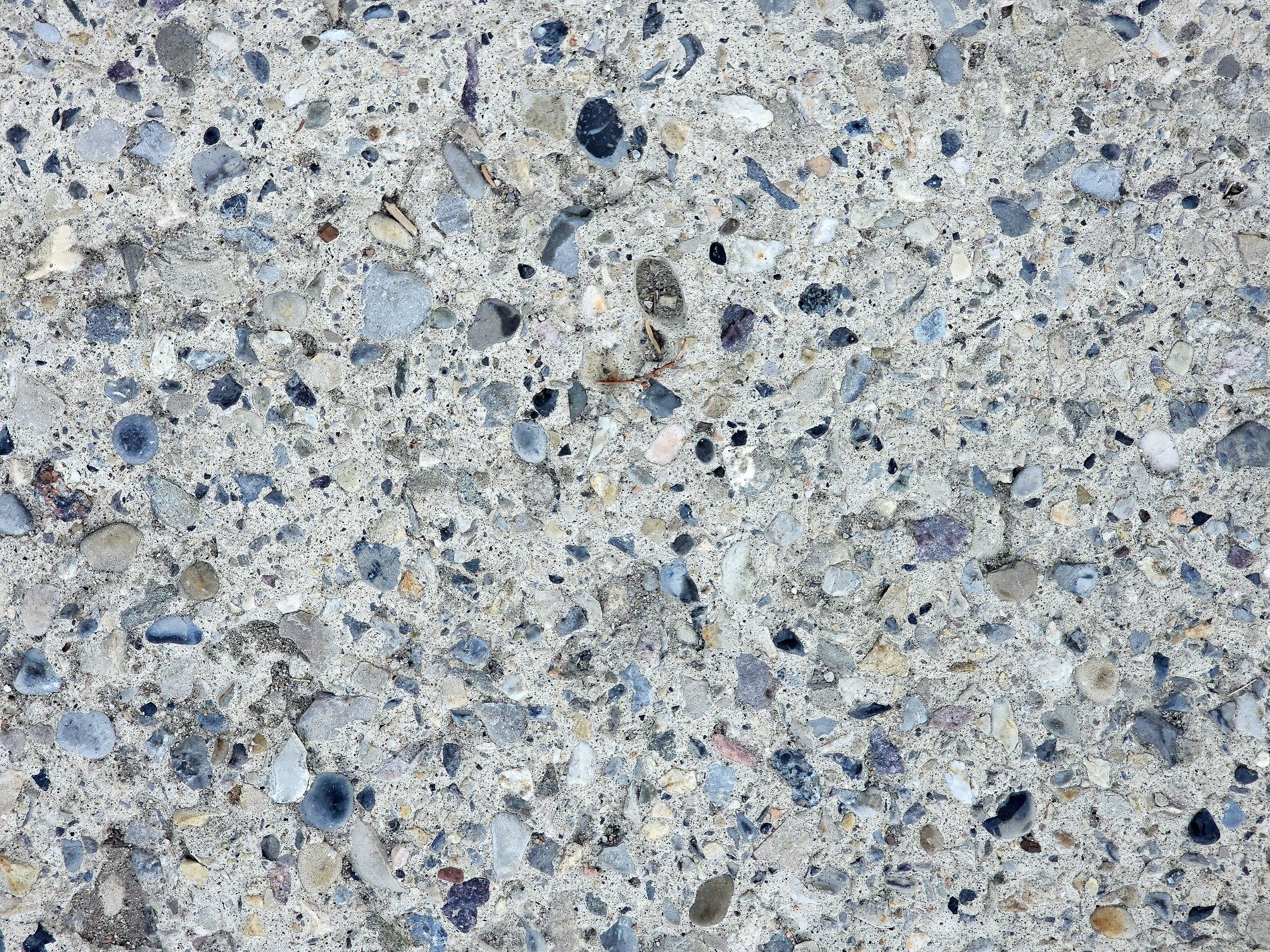 Grey stones in the mix, rough concrete holds the grit, time wears the finish