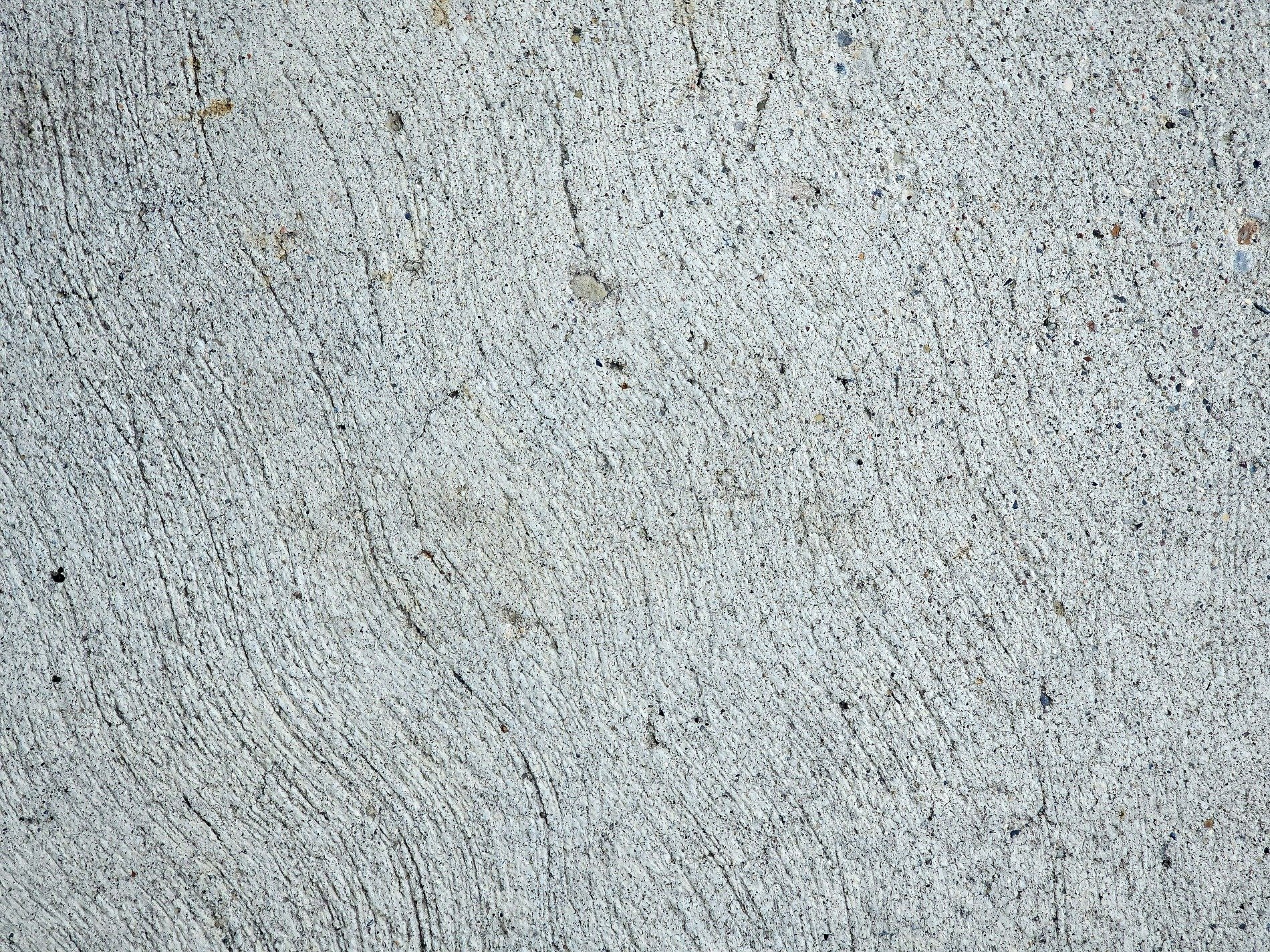 Rough gray surface set, sweeping lines cross cold cement, grit and stone remain