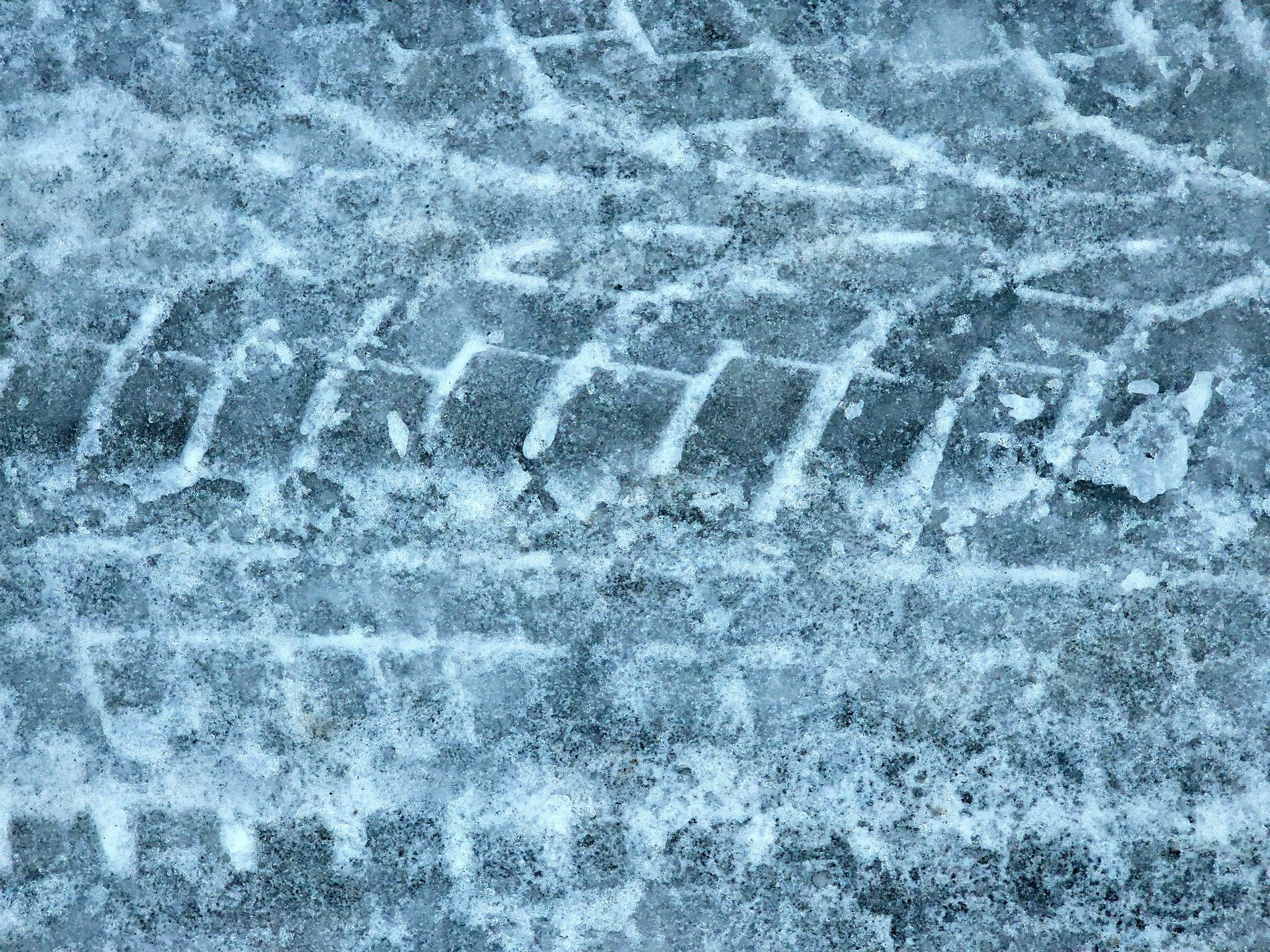 Frozen tracks in ice, rubber treads press deep in slush, winter's passing path