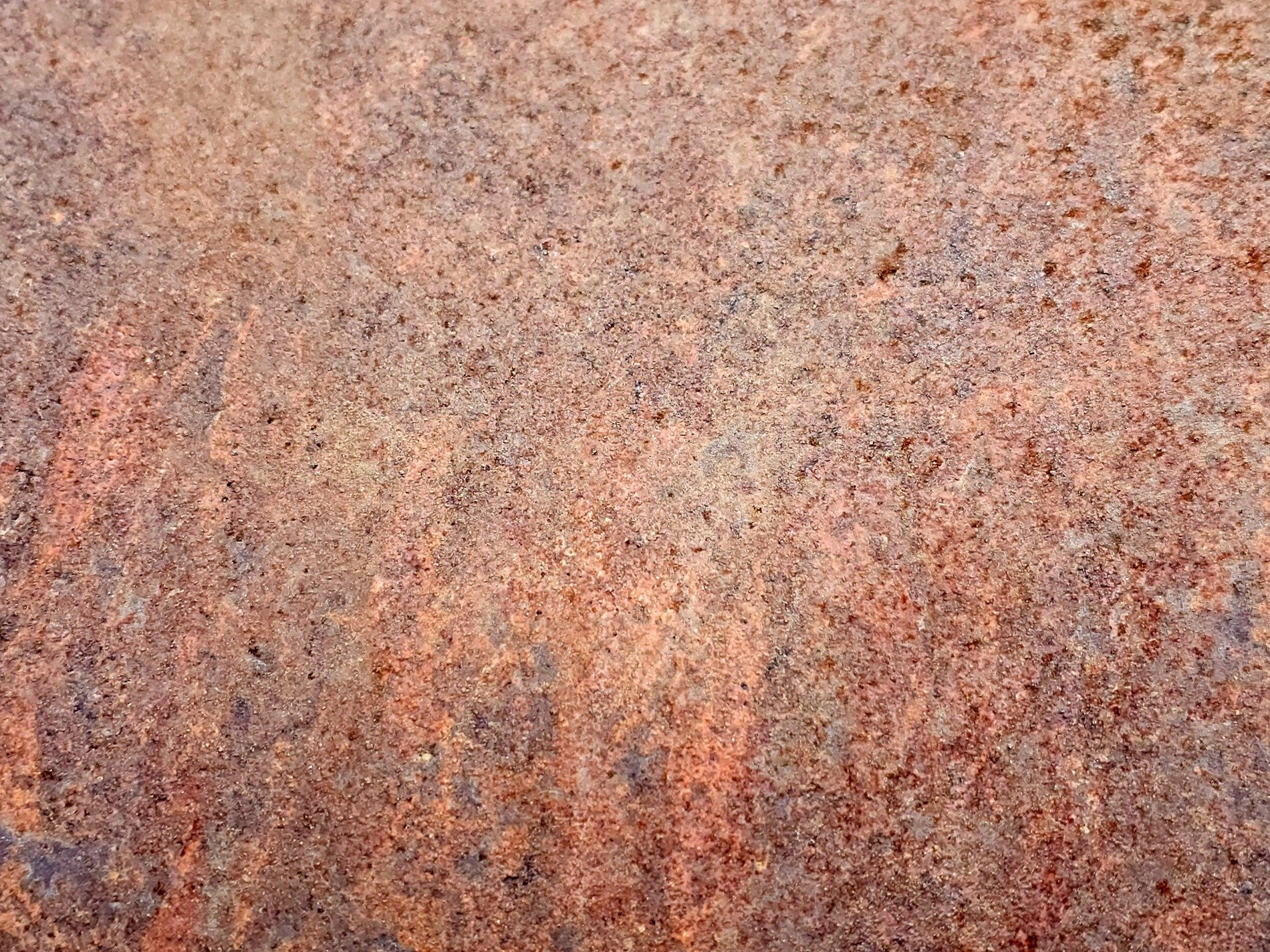 Heavy rust scales, orange and brown minerals claim the steel, grit holds the decay