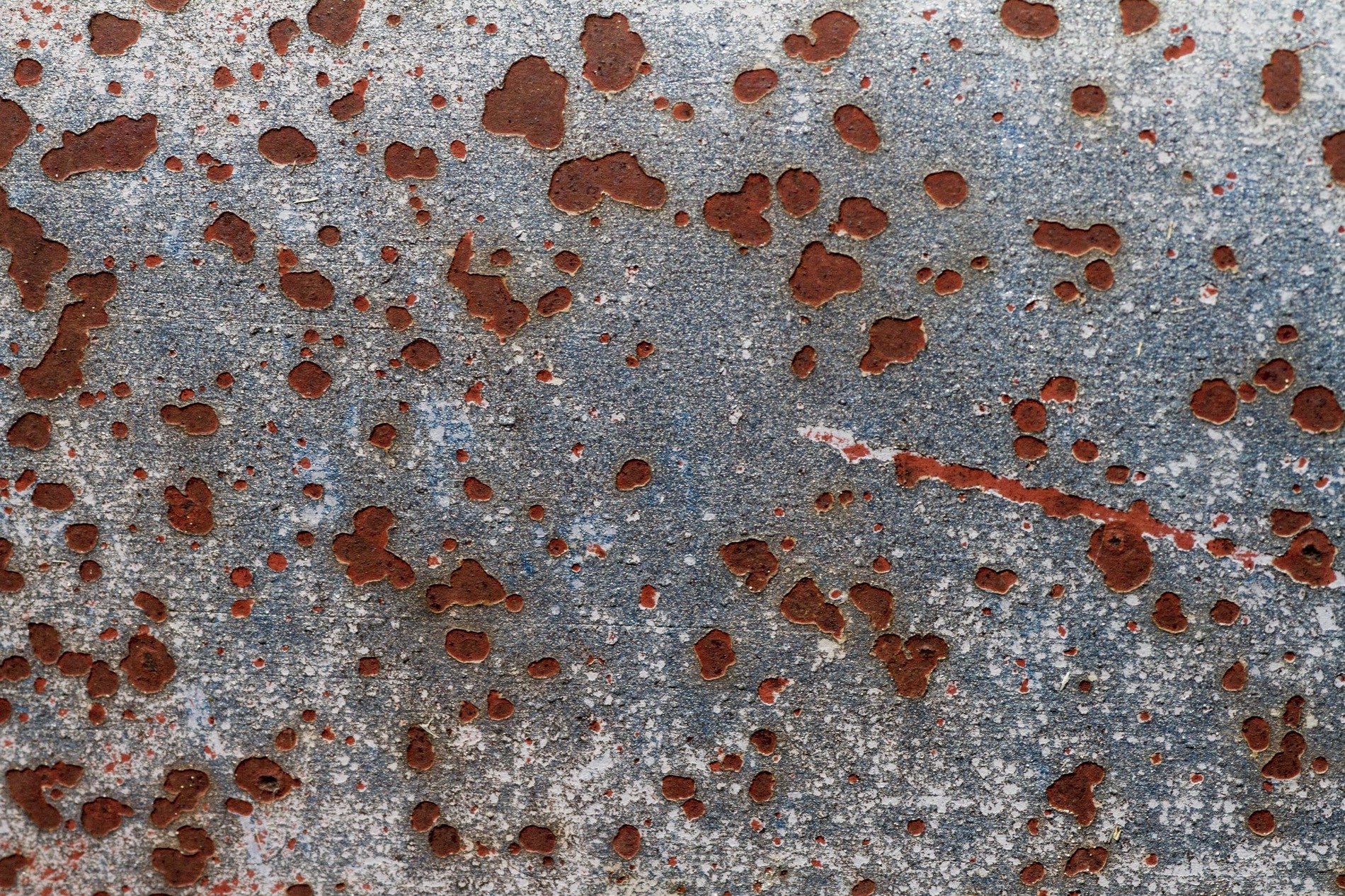 Orange dust on blue, cracked skin peels from heavy steel, rust claims the finish