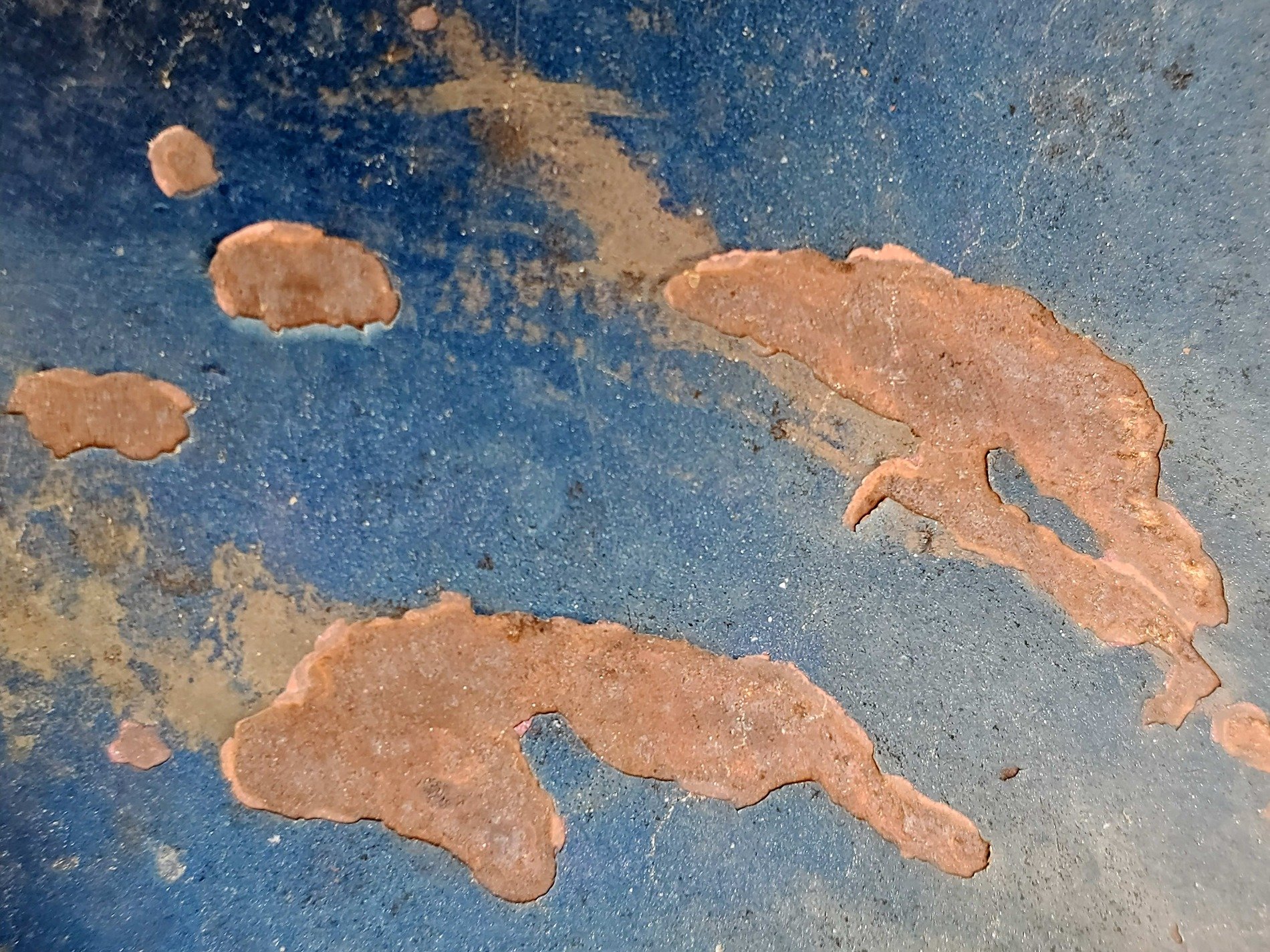 Blue paint flakes away, orange islands rise in sea, iron meets the air