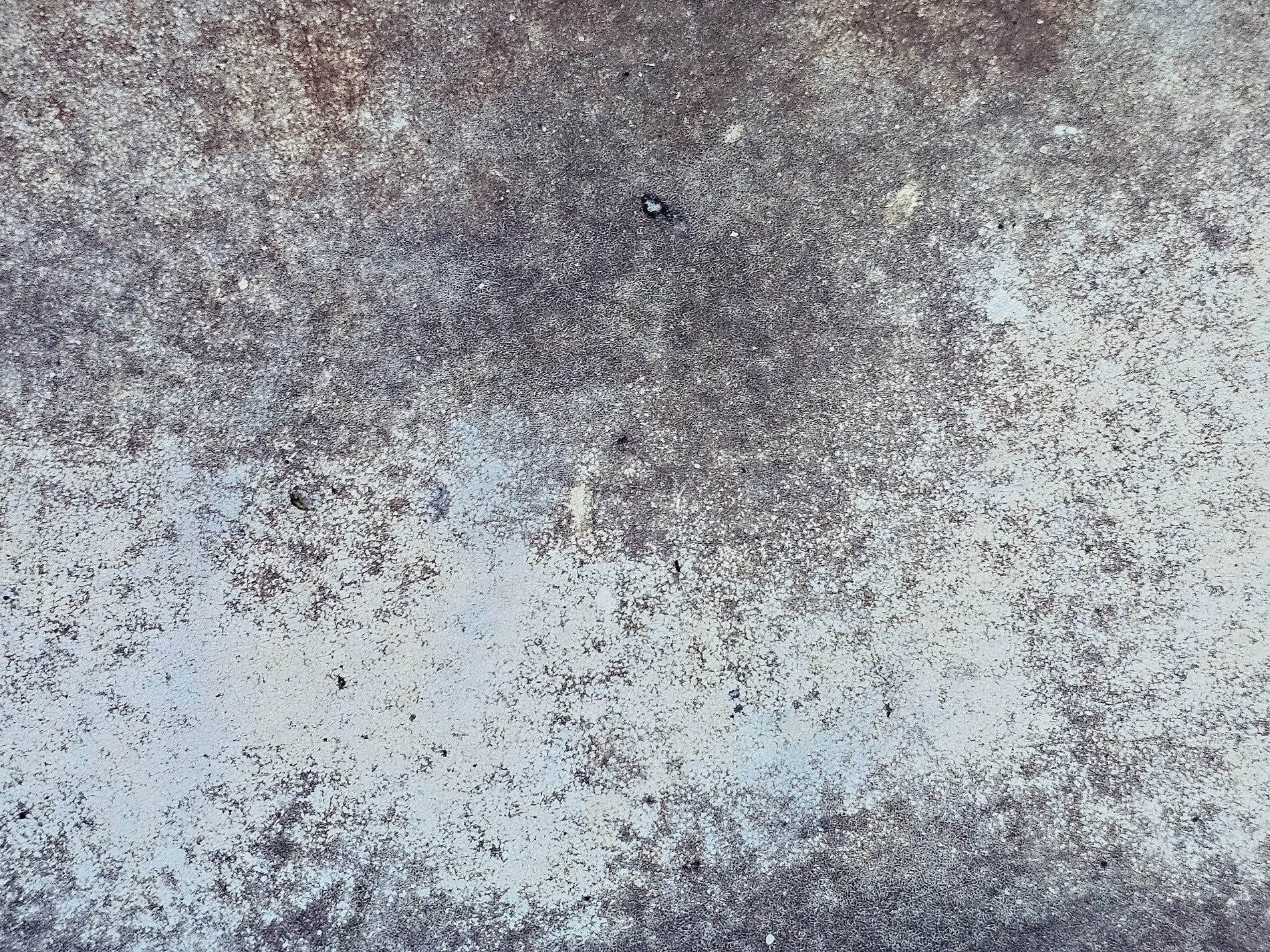 Faint white paint recedes, cracked and worn by passing time, rough stone breathes beneath