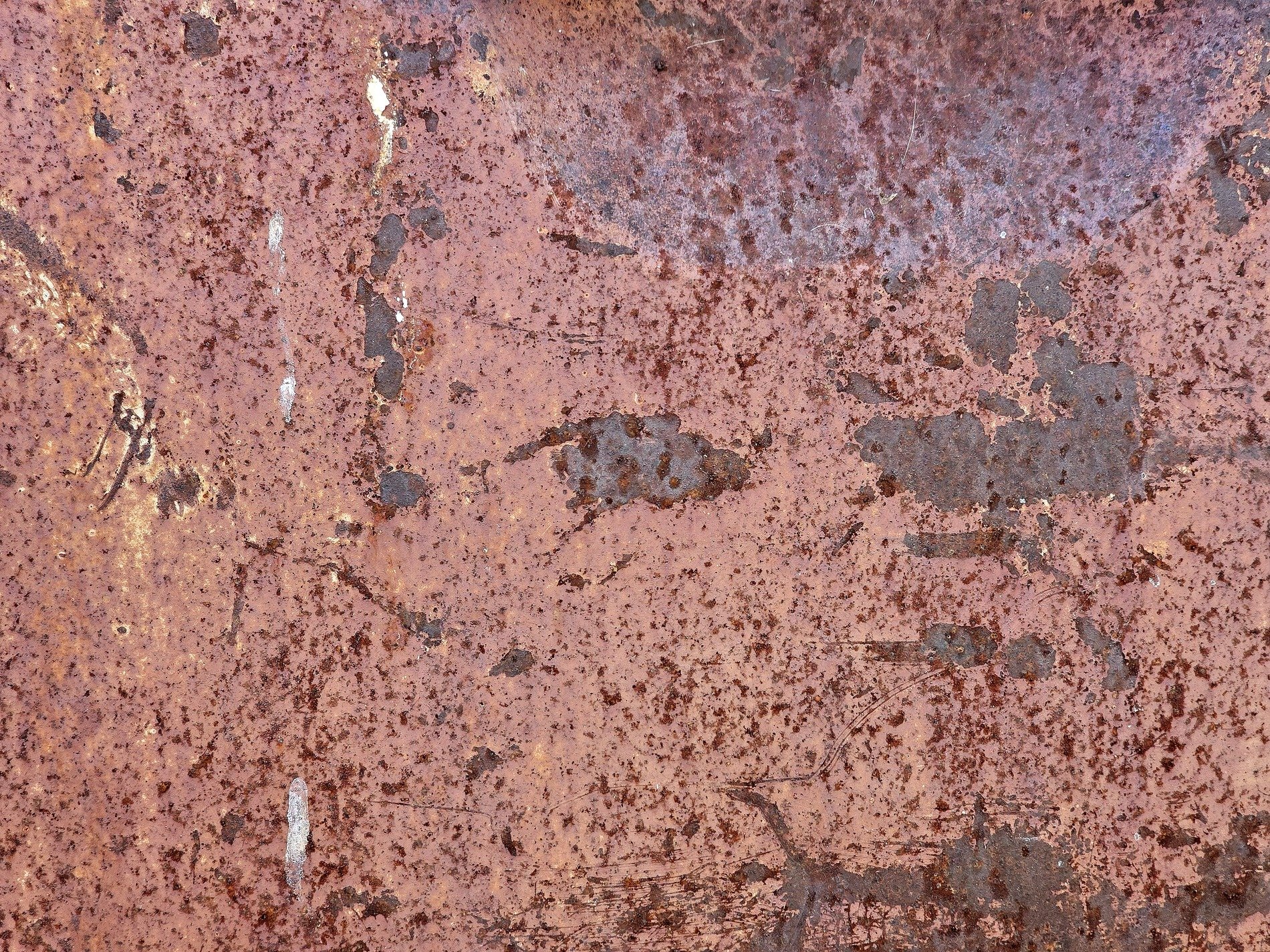 Pink rust coats the steel, dark scars break the fading red, time leaves heavy grit