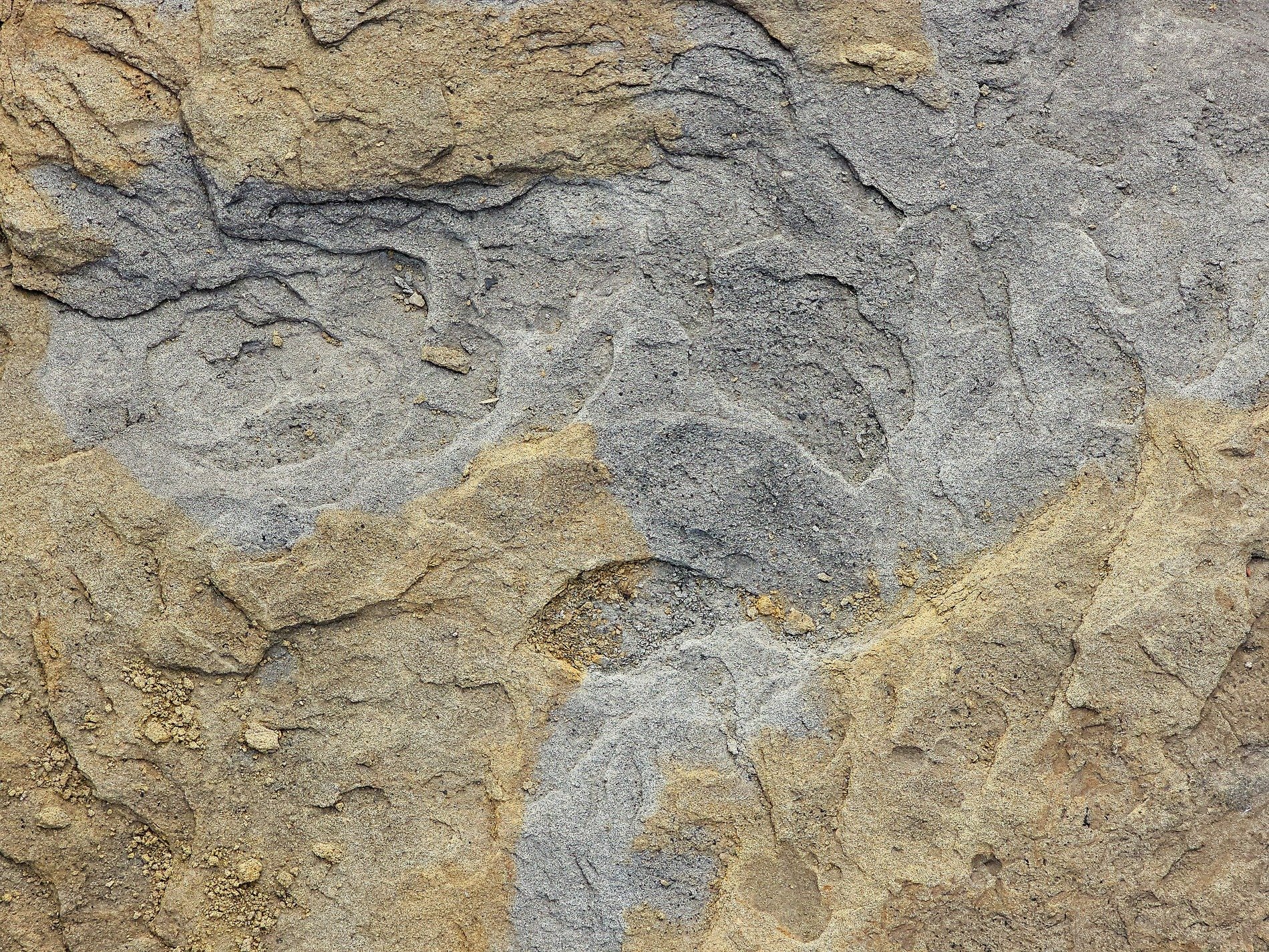 Gray stone layers shift, sand and grit cover the face, time wears down the edge