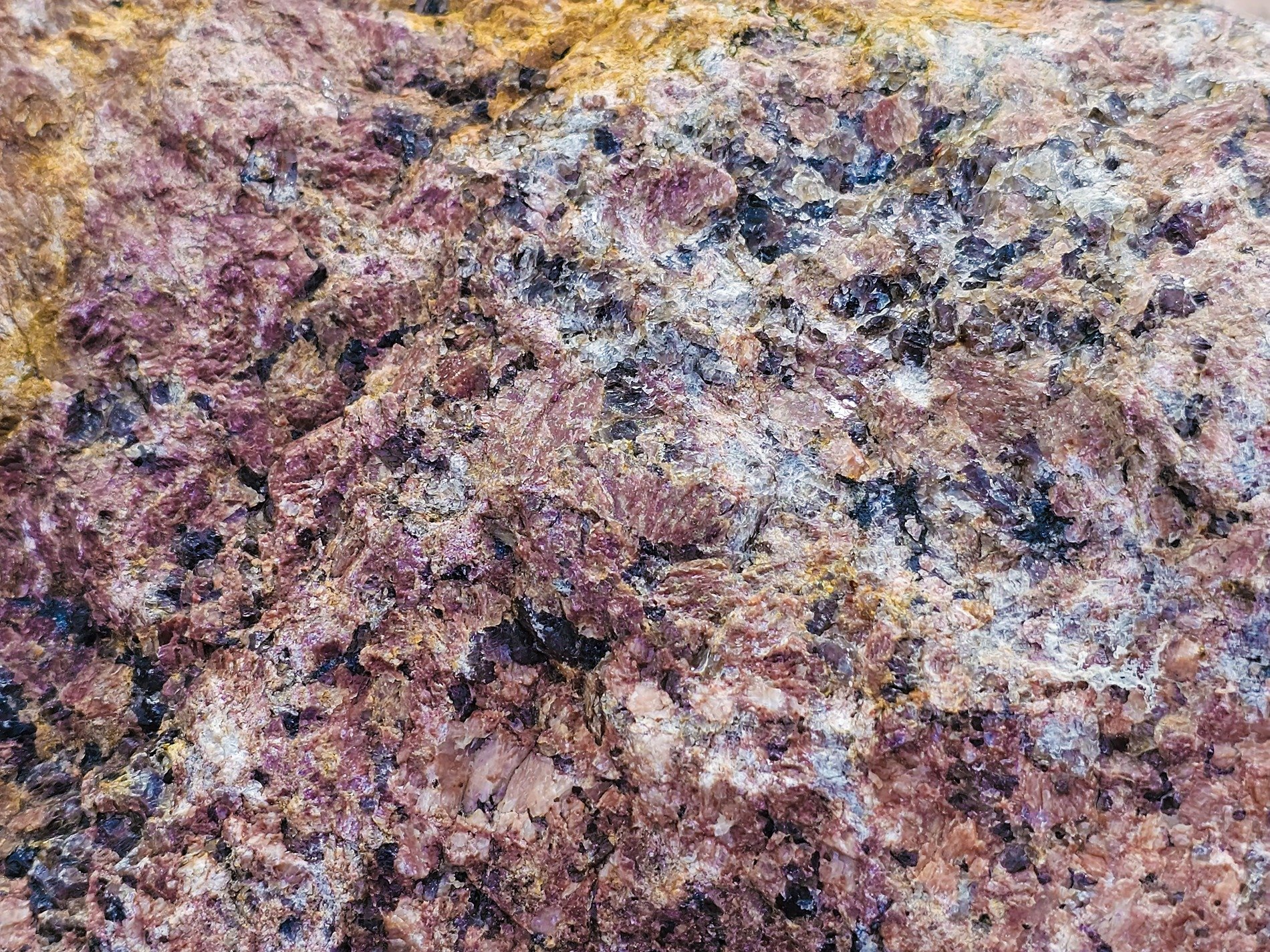 Pink crystals cluster, dark minerals dot the face, earth's hard heart revealed