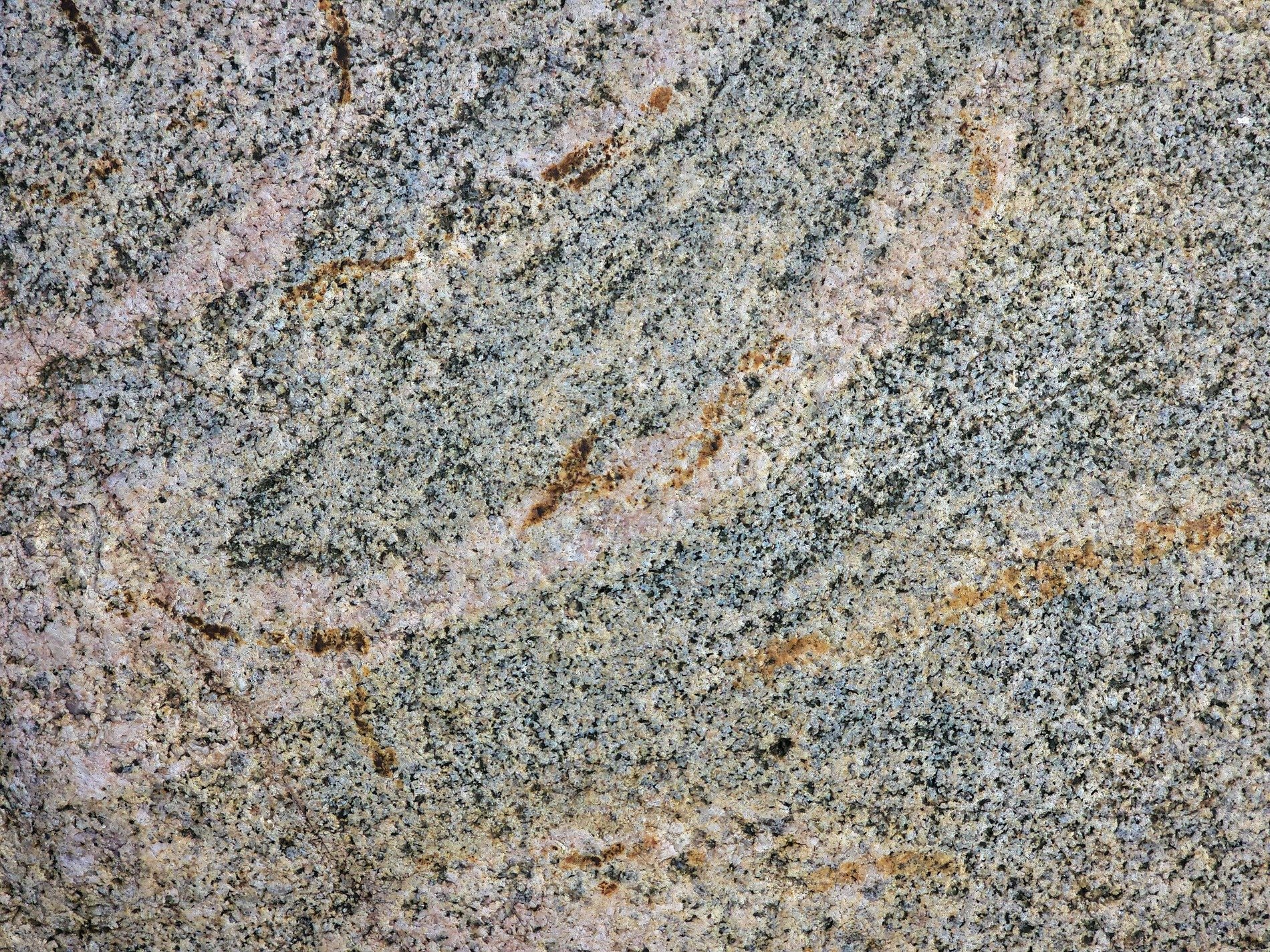 Pink veins in the grey, black specks scatter on the stone, grit holds the pattern
