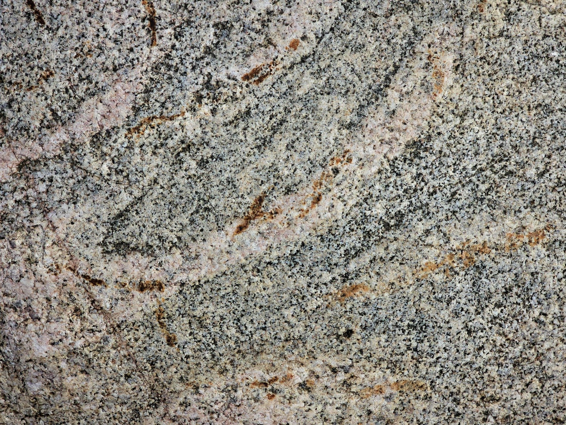 Grains of speckled grey, orange veins map out the past, solid ancient stone