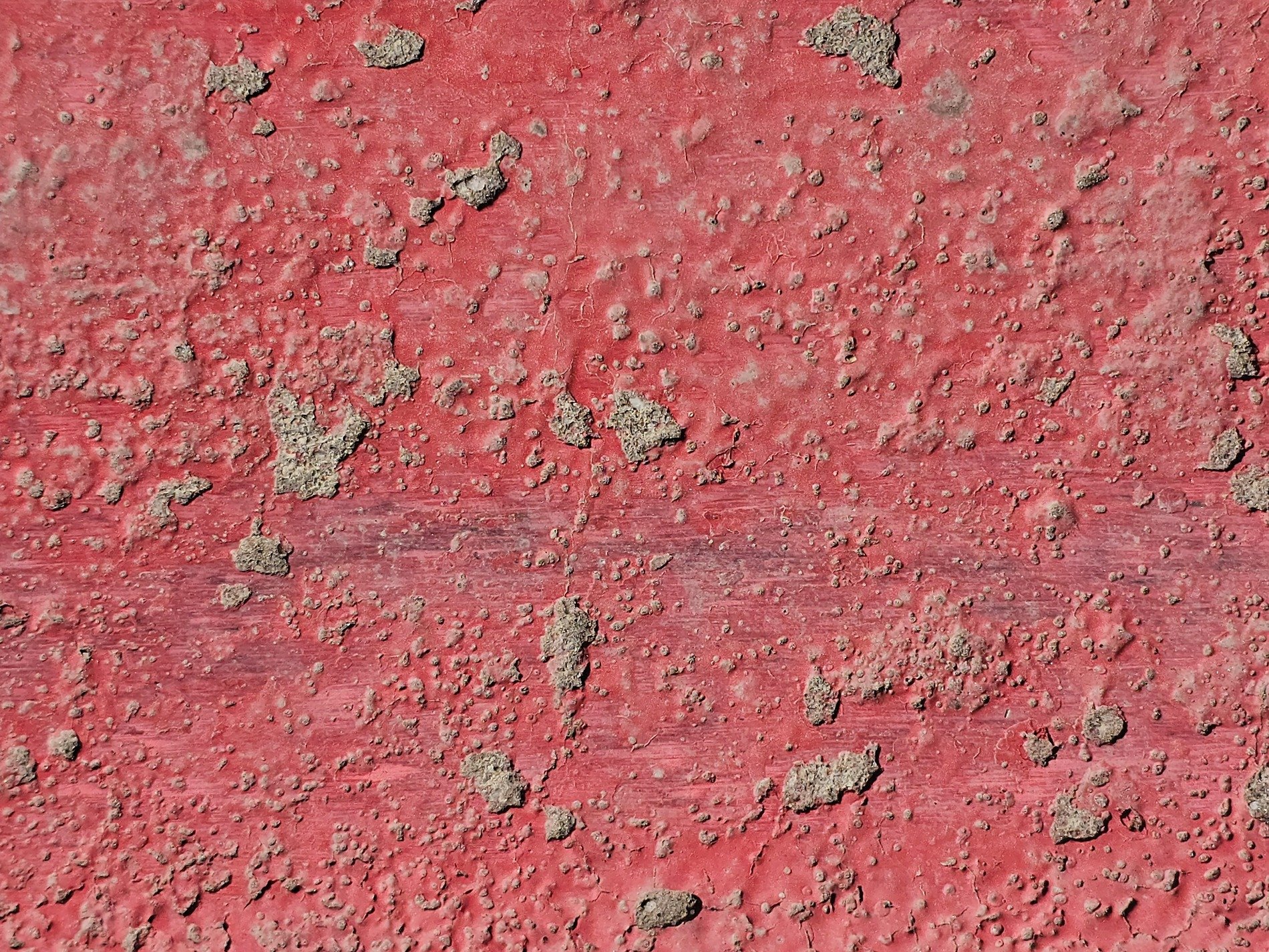 Red paint on eroded curb, rough concrete pits meet the road, grit marks the finish