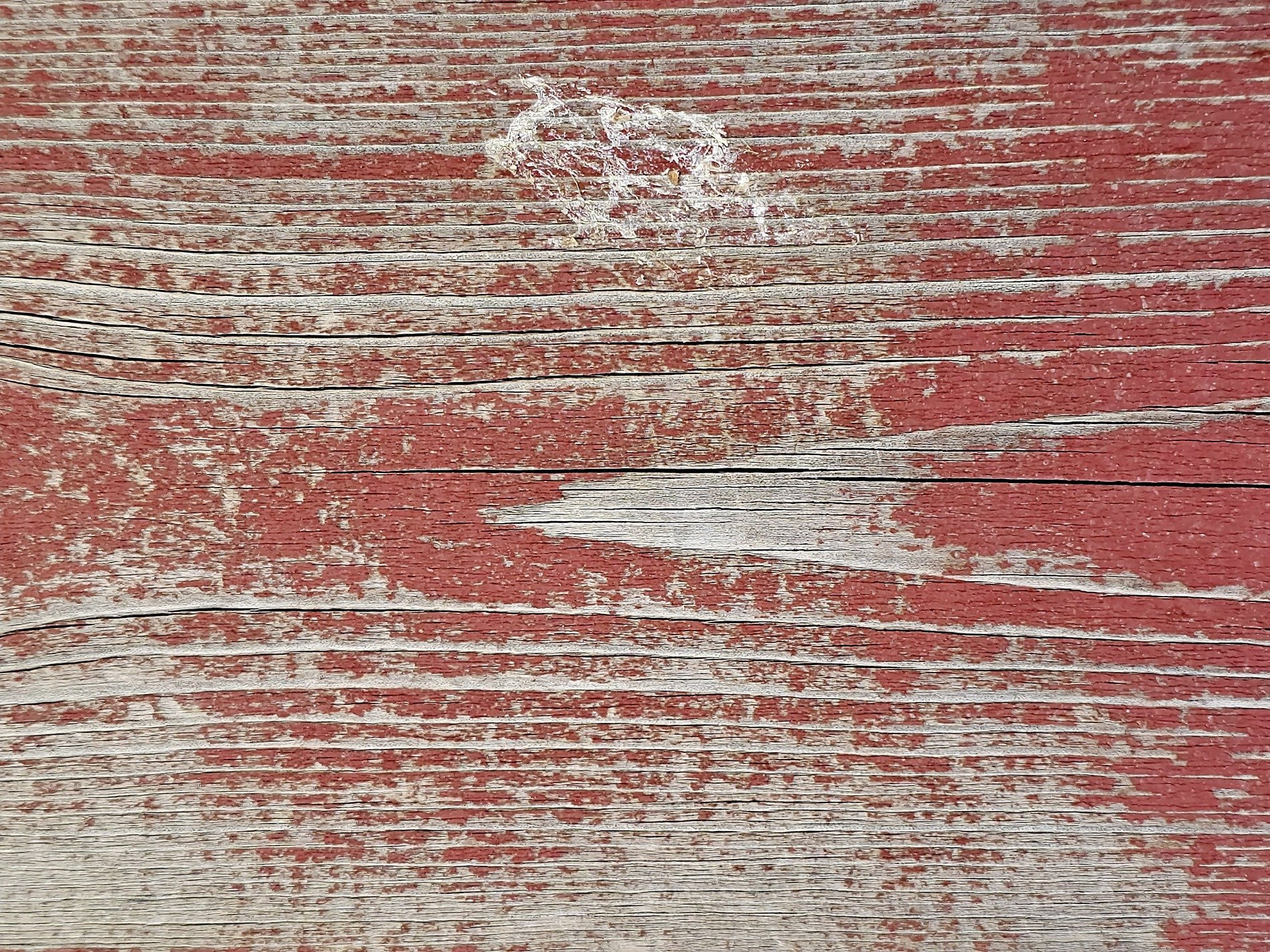 Red paint on the wood, weathered grain shows through the cracks, old years leave a mark