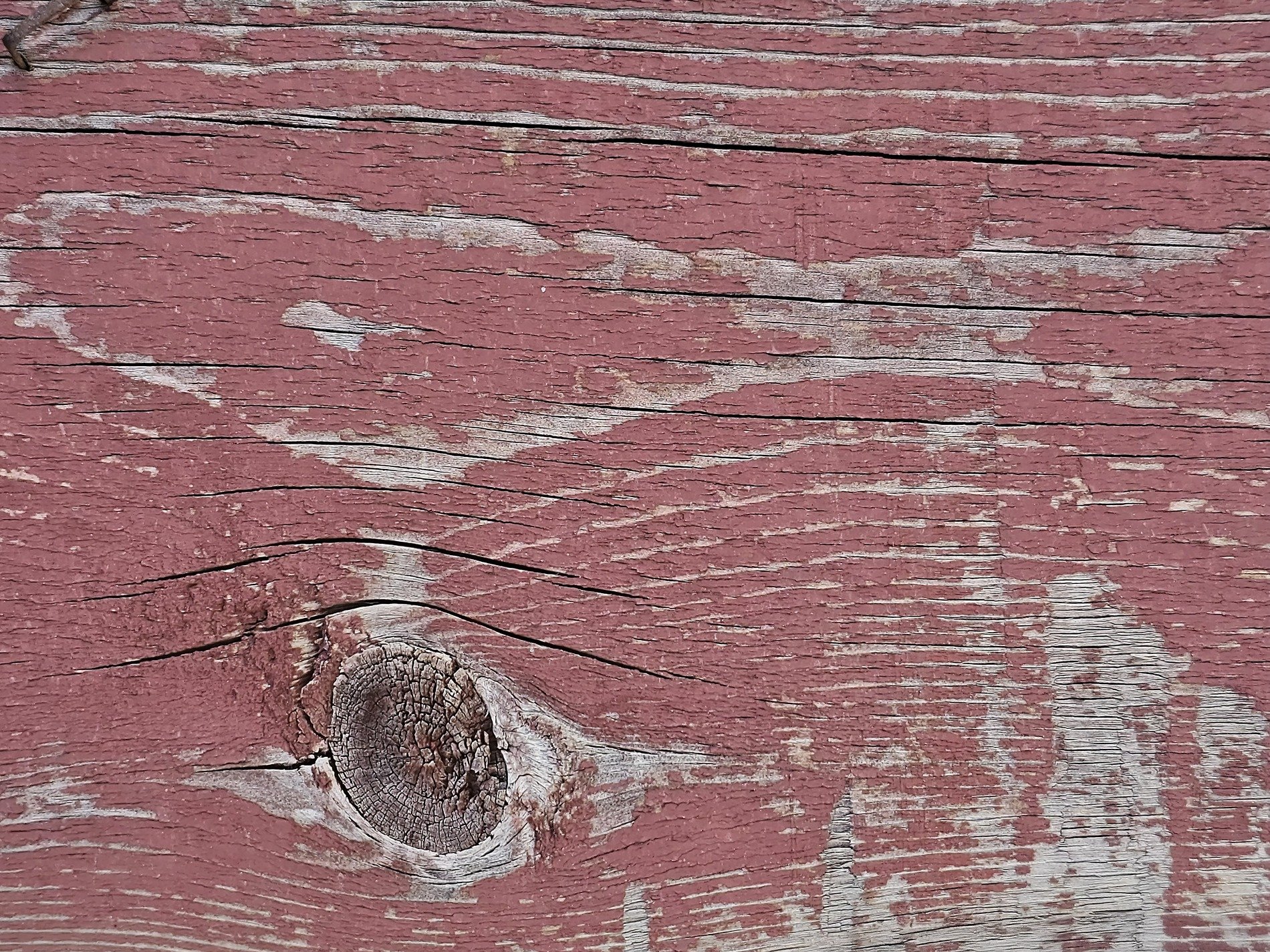 Red paint wears away, wood knot watches the seasons, grain tells a story