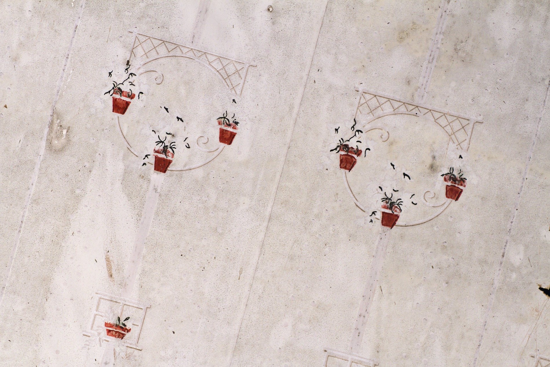 Red pots on the wall, faded lattice lines the white, pattern holds the age