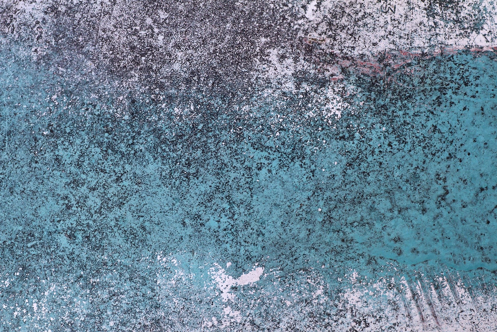 Teal paint wears away, dark grit hides in deep craters, time erodes the stone