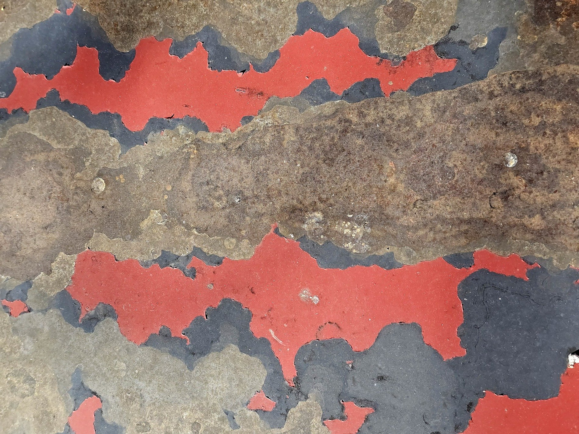 Red skin peels away, brown rust eats the heavy steel, flakes drift in the air