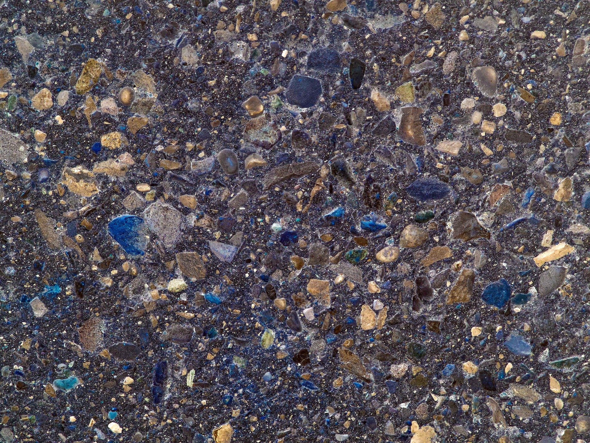 Rough aggregate grains, grey depths show beneath, grit marks the clump