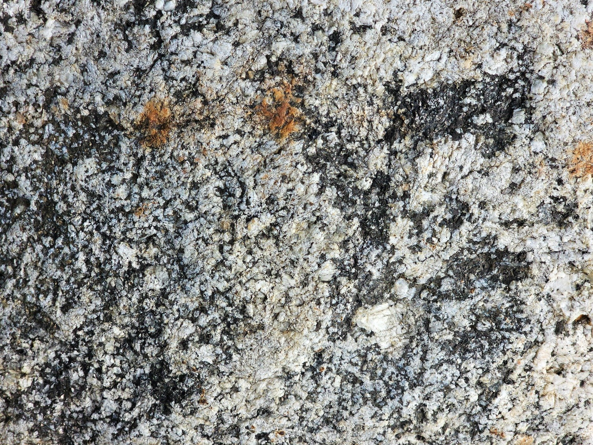 Rough aggregate in the mix, grey concrete holds the stones, time wears the pavement