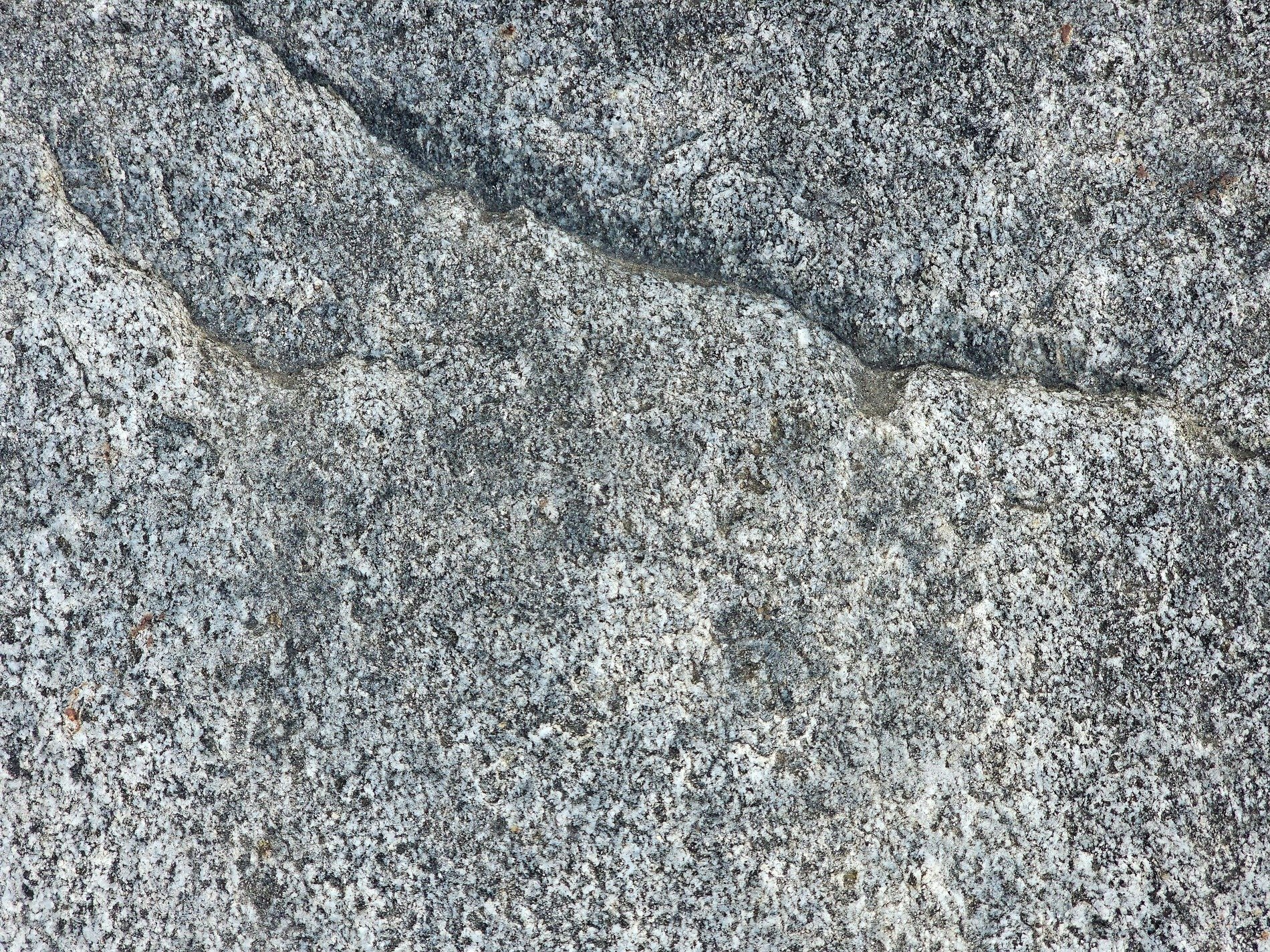 Rough granite surface, grey stone meets a jagged ridge, ancient frozen dust