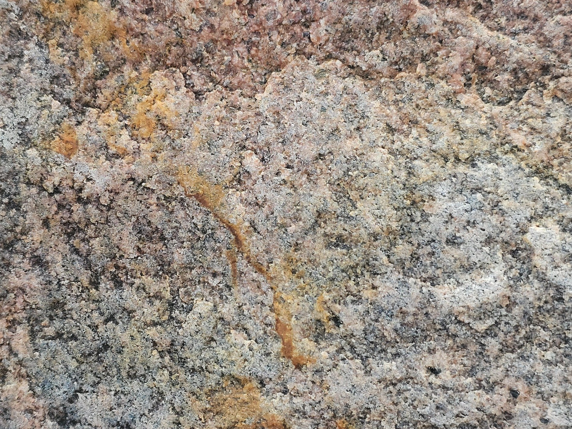 Rough stone greets the day, rusty veins cut through the grain, time carves out the depth