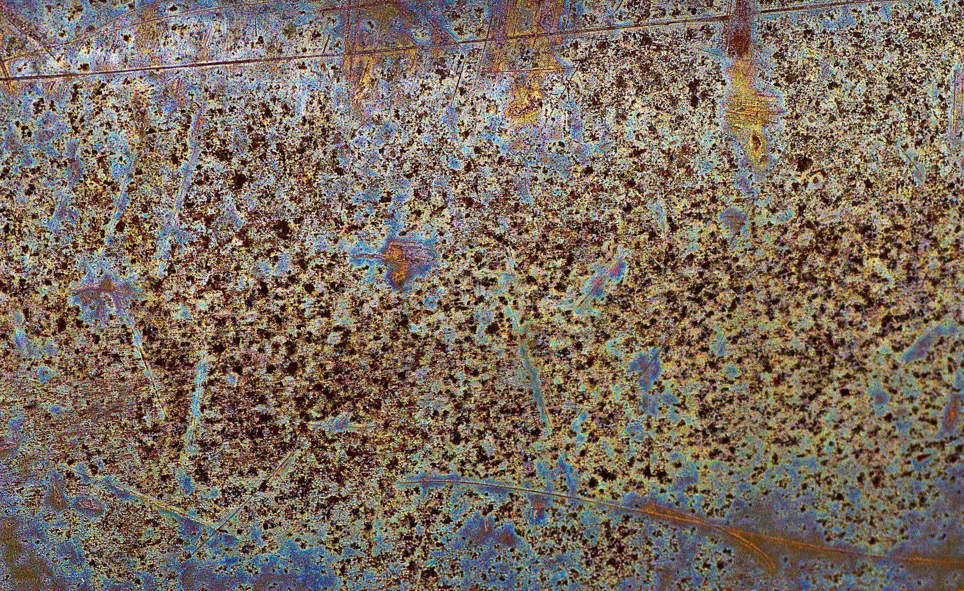 Silver metal pitted, grey circles mark the heavy plate, grit holds the finish