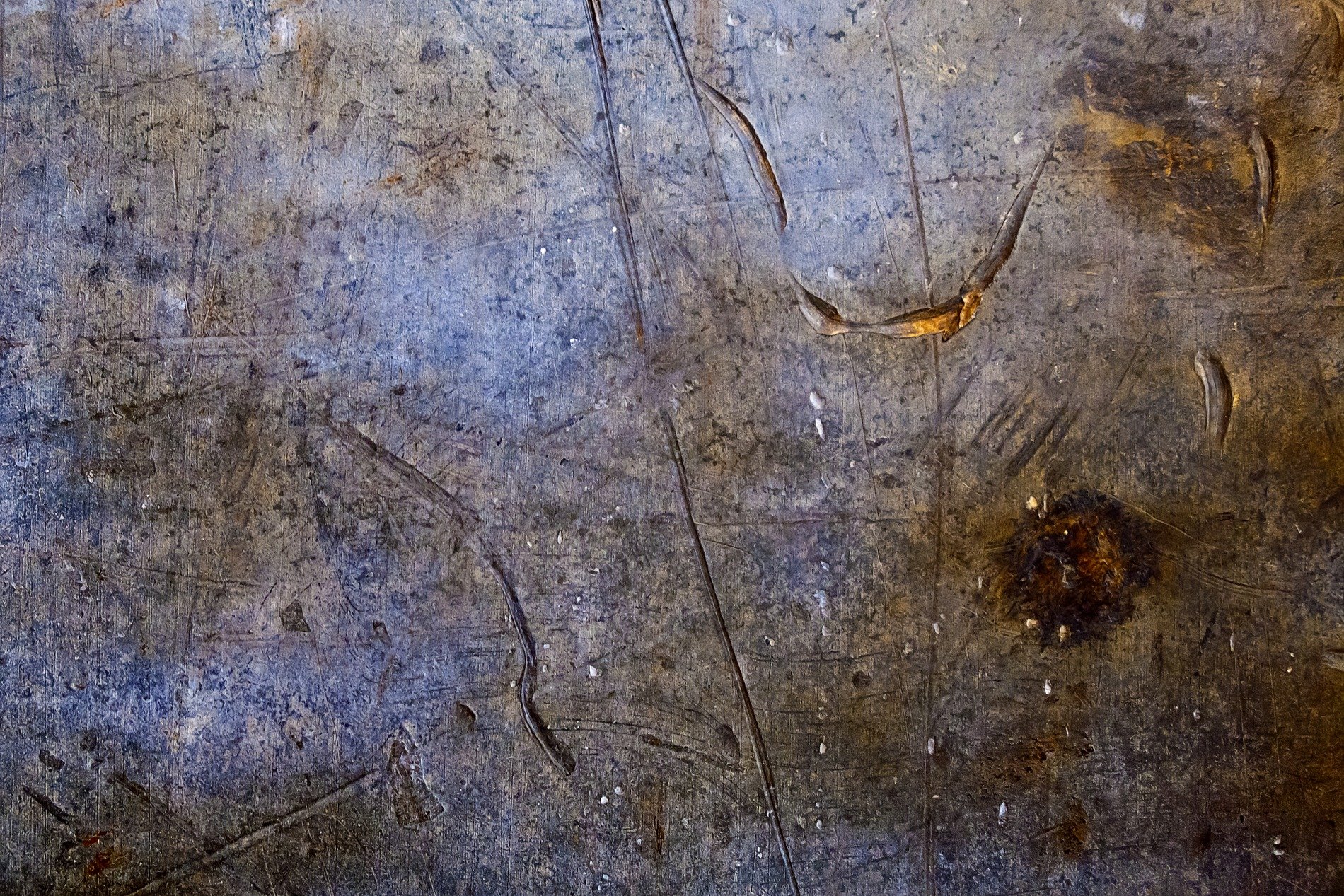 Steel scarred by usage, deep gouges cut the surface, rust blooms in the dark