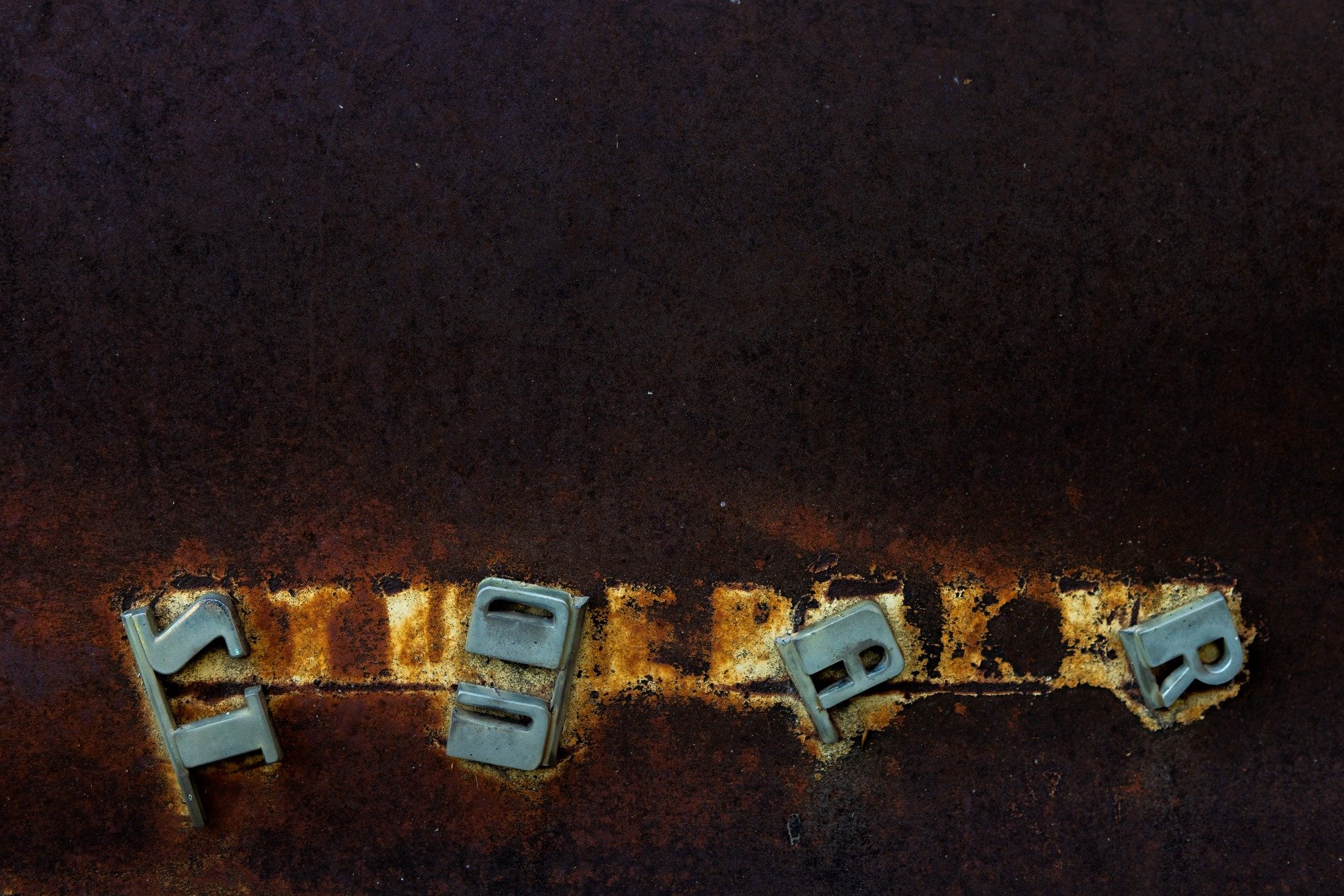 Chrome letters tumble, rust devours the iron skin, words lost to the years